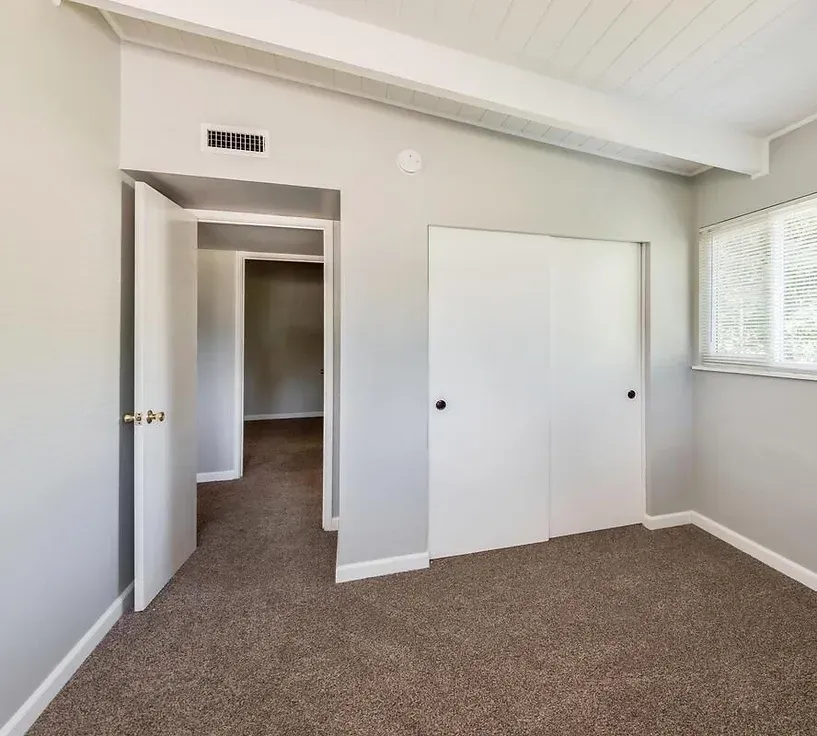 An empty bedroom with a closet and a window