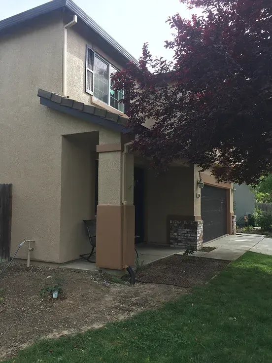 A house with a garage and a tree in front of it