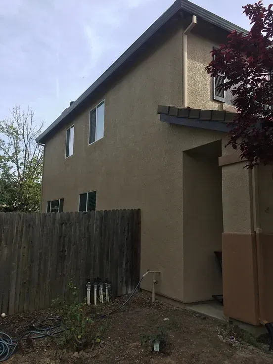 A house with a fence and a tree in front of it.