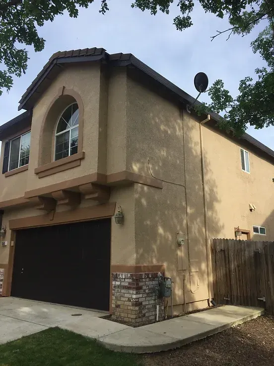 A large tan house with a black garage door
