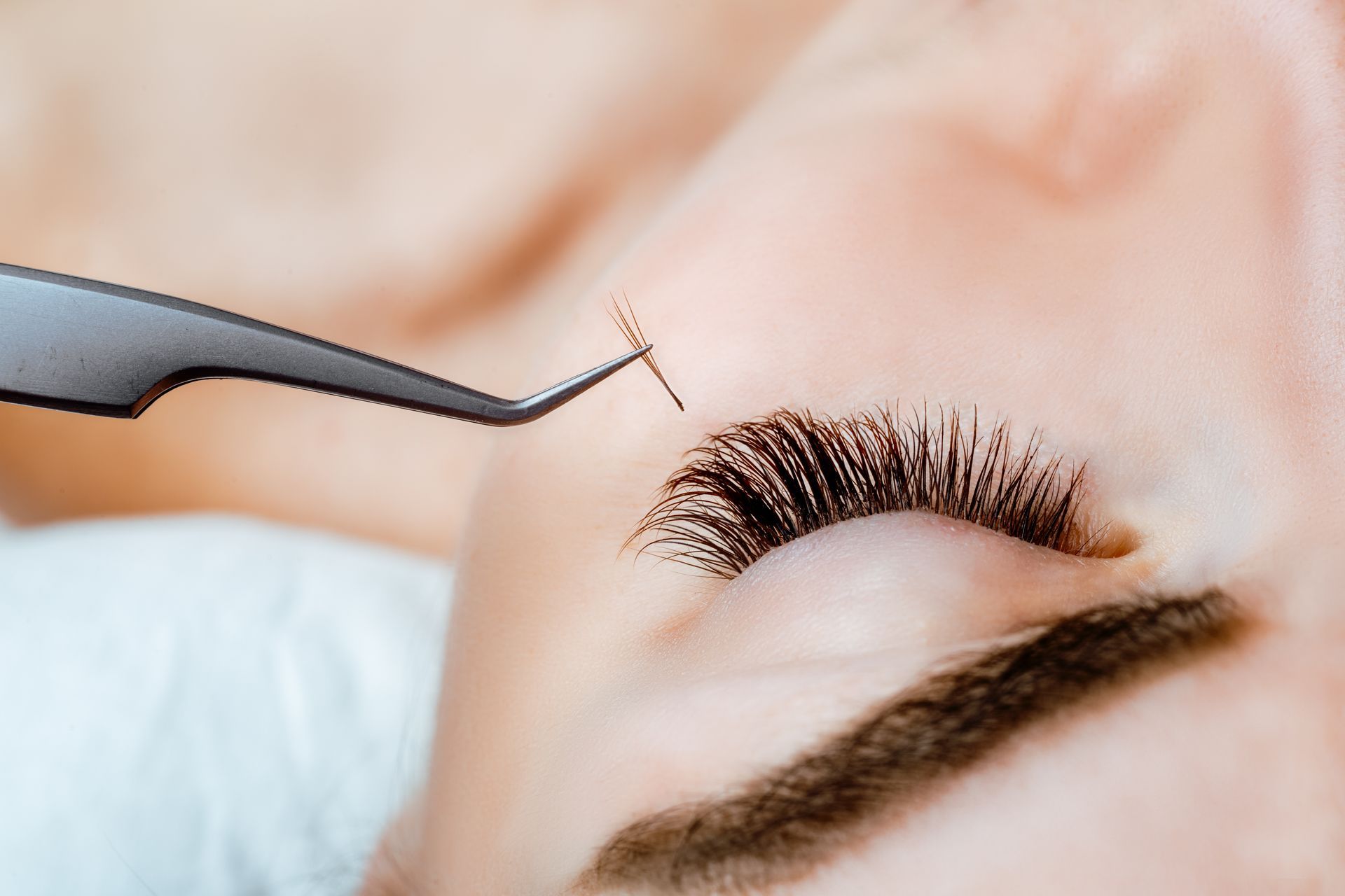 A close up of a woman 's eye with a pair of tweezers.