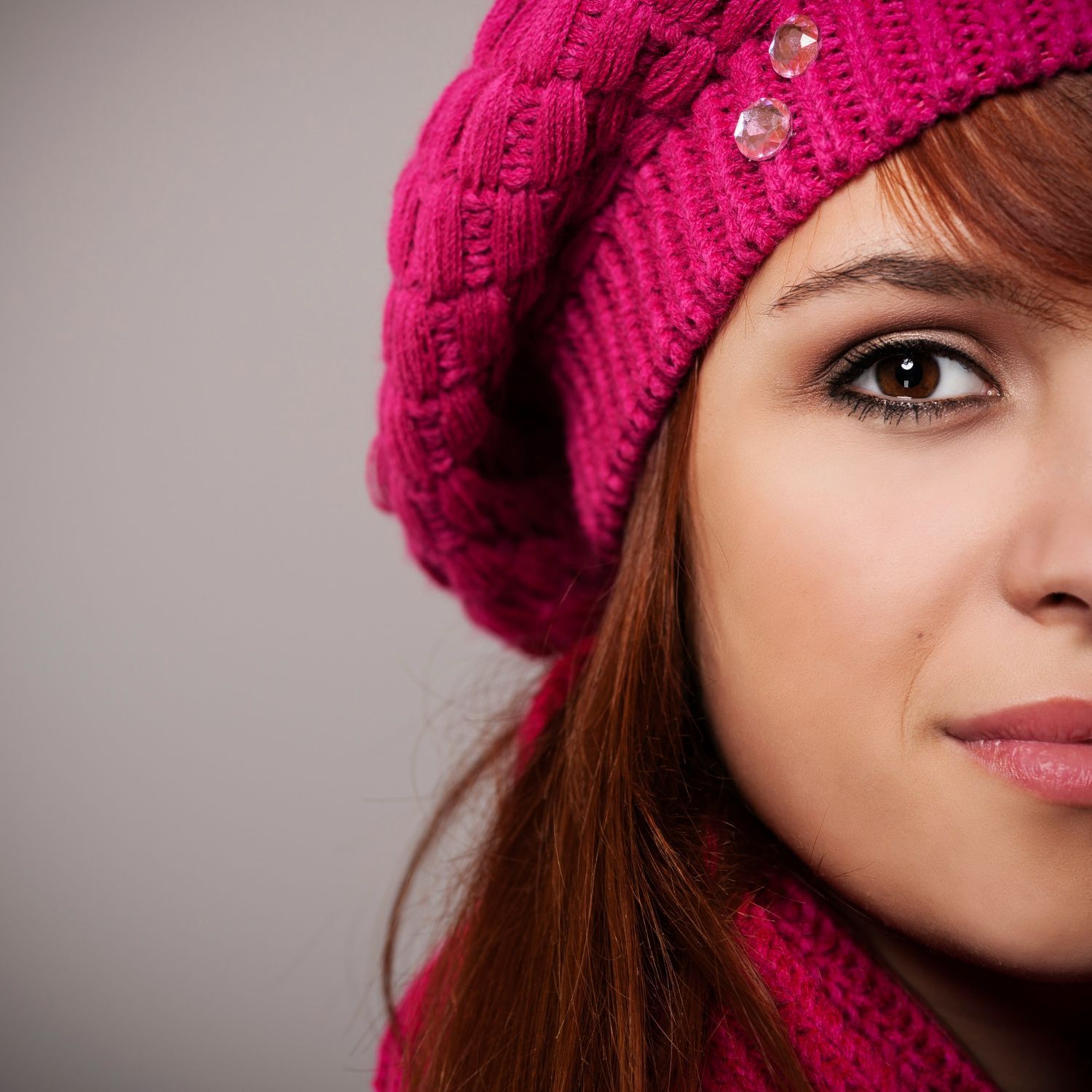 A close up of a woman wearing a pink hat and scarf.