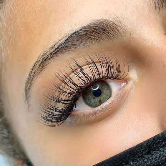 A close up of a woman 's eye with long eyelashes.