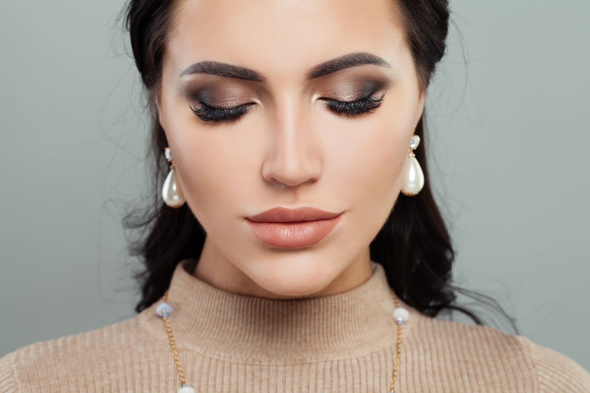 A close up of a woman wearing a sweater and pearl earrings.