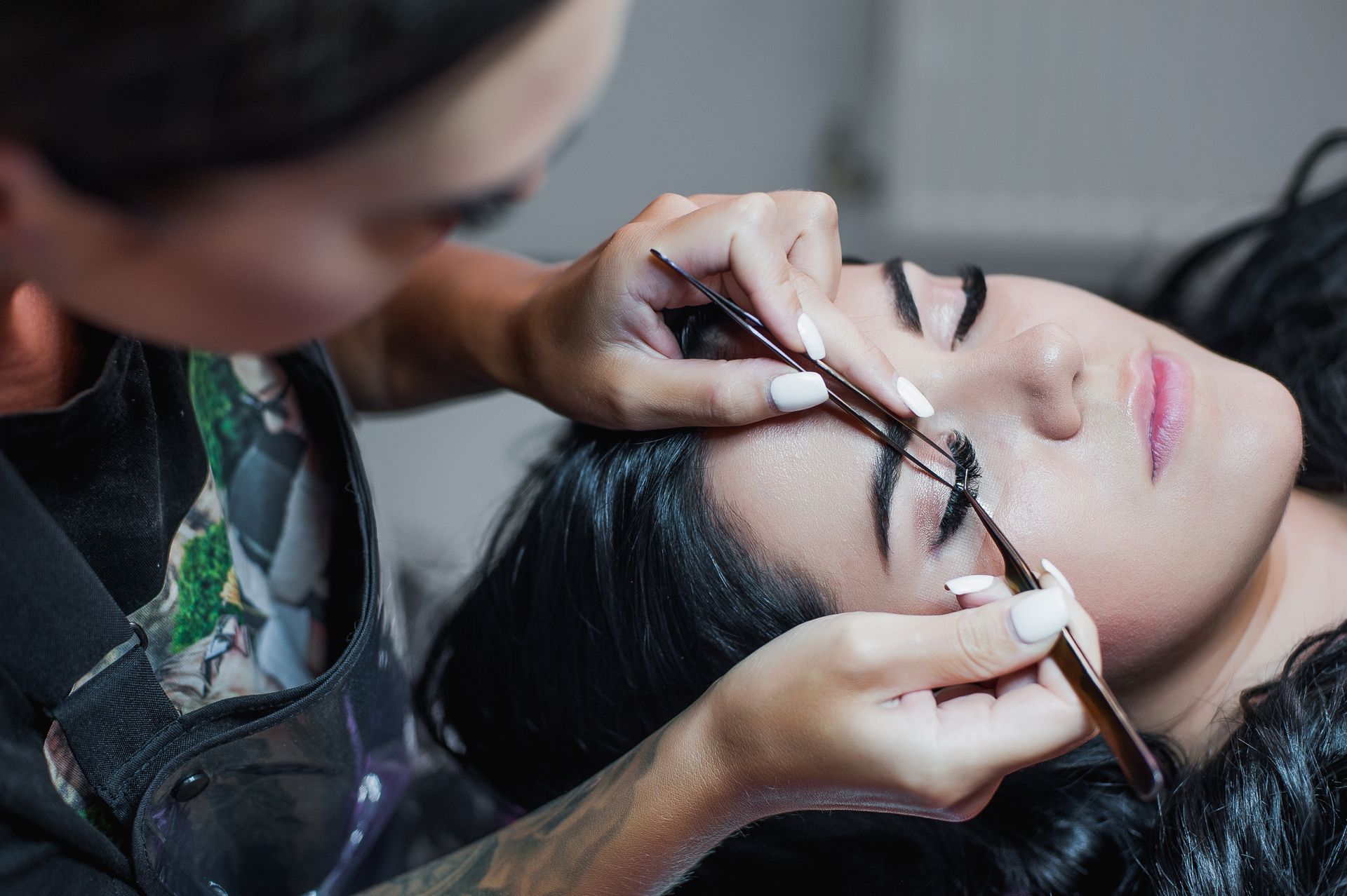 A woman is getting her eyebrows done by a makeup artist.