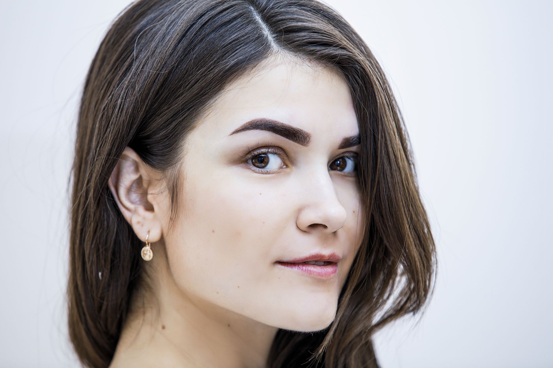 A close up of a woman 's face with long hair and earrings.