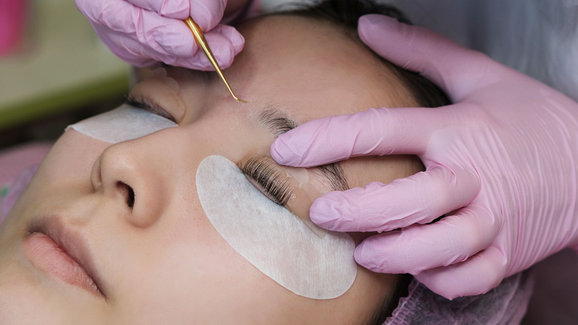 A woman is getting eyelash extensions in a beauty salon.