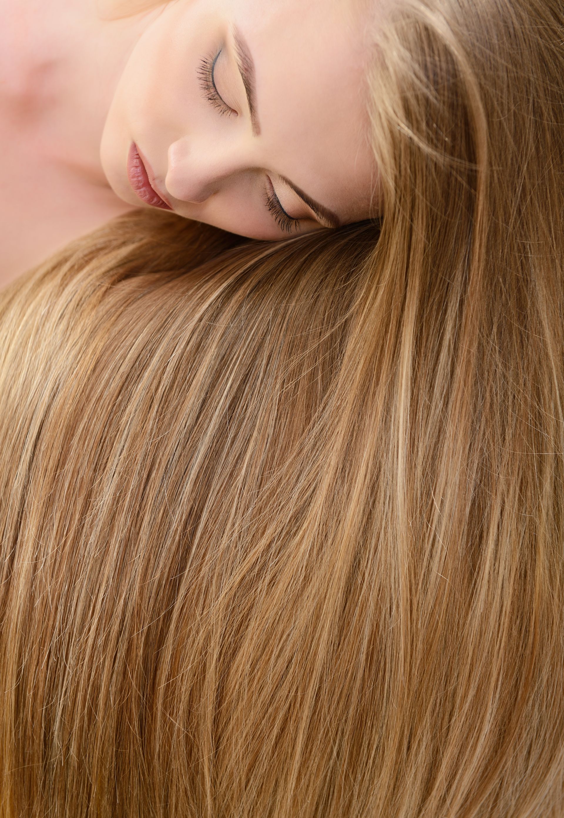 A woman is laying down with her head on her long blonde hair.