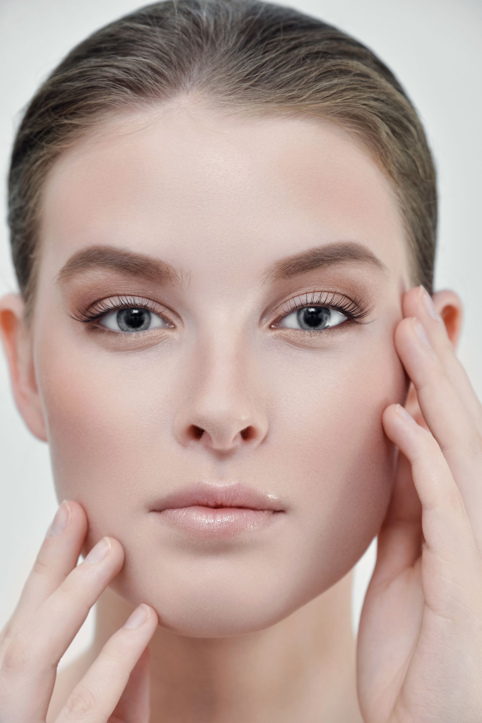 A close up of a woman 's face with her hands on it.