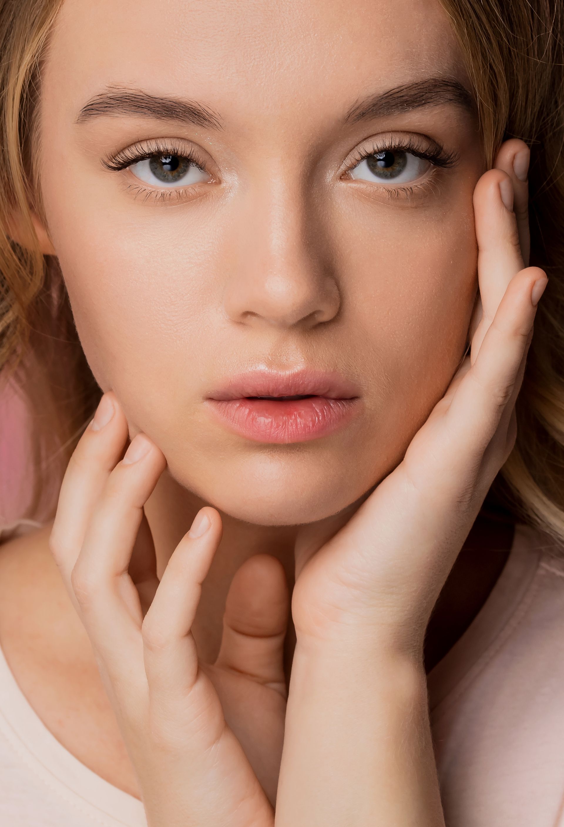 A close up of a woman 's face with her hands on it.