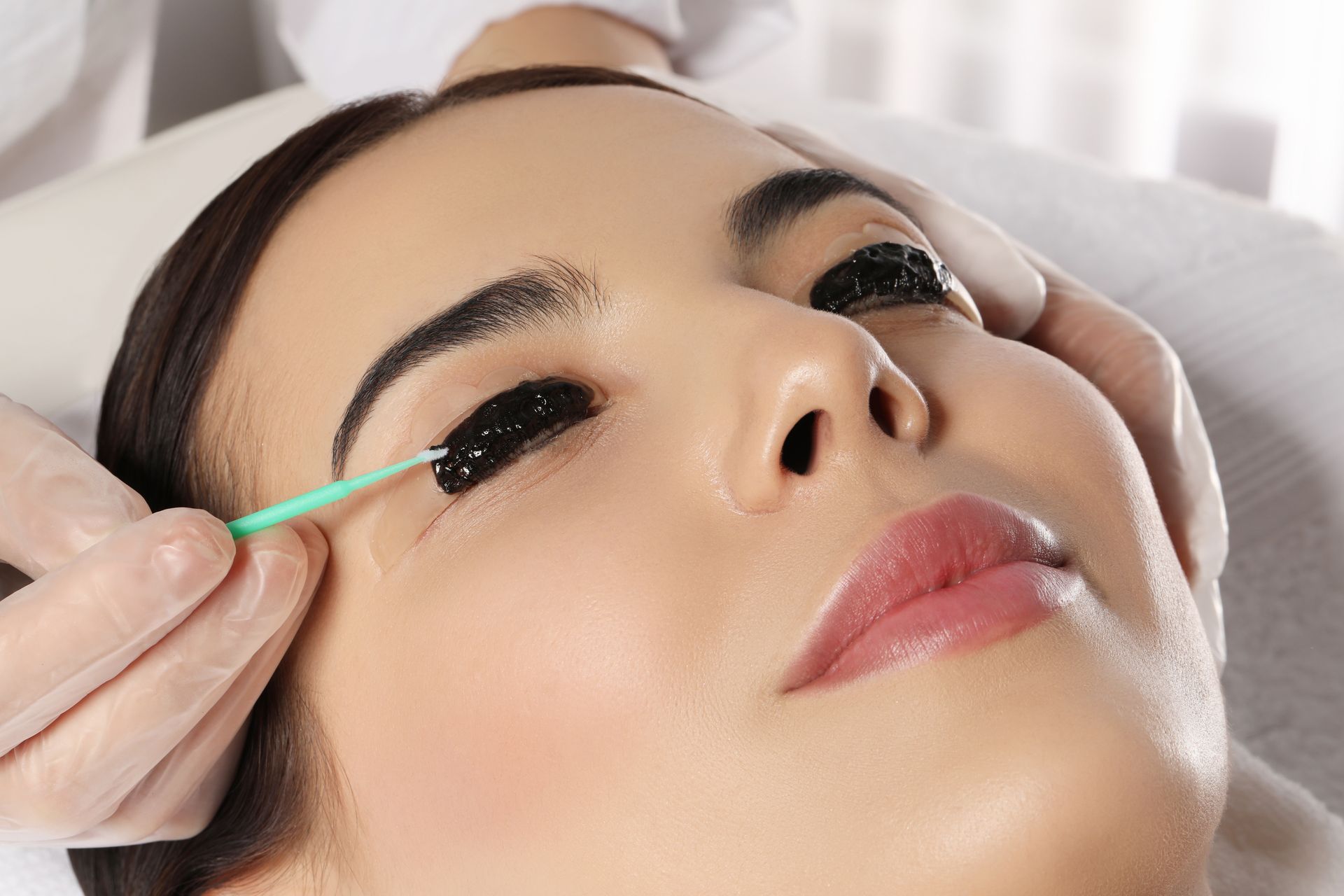 A woman is getting her eyelashes done at a beauty salon.