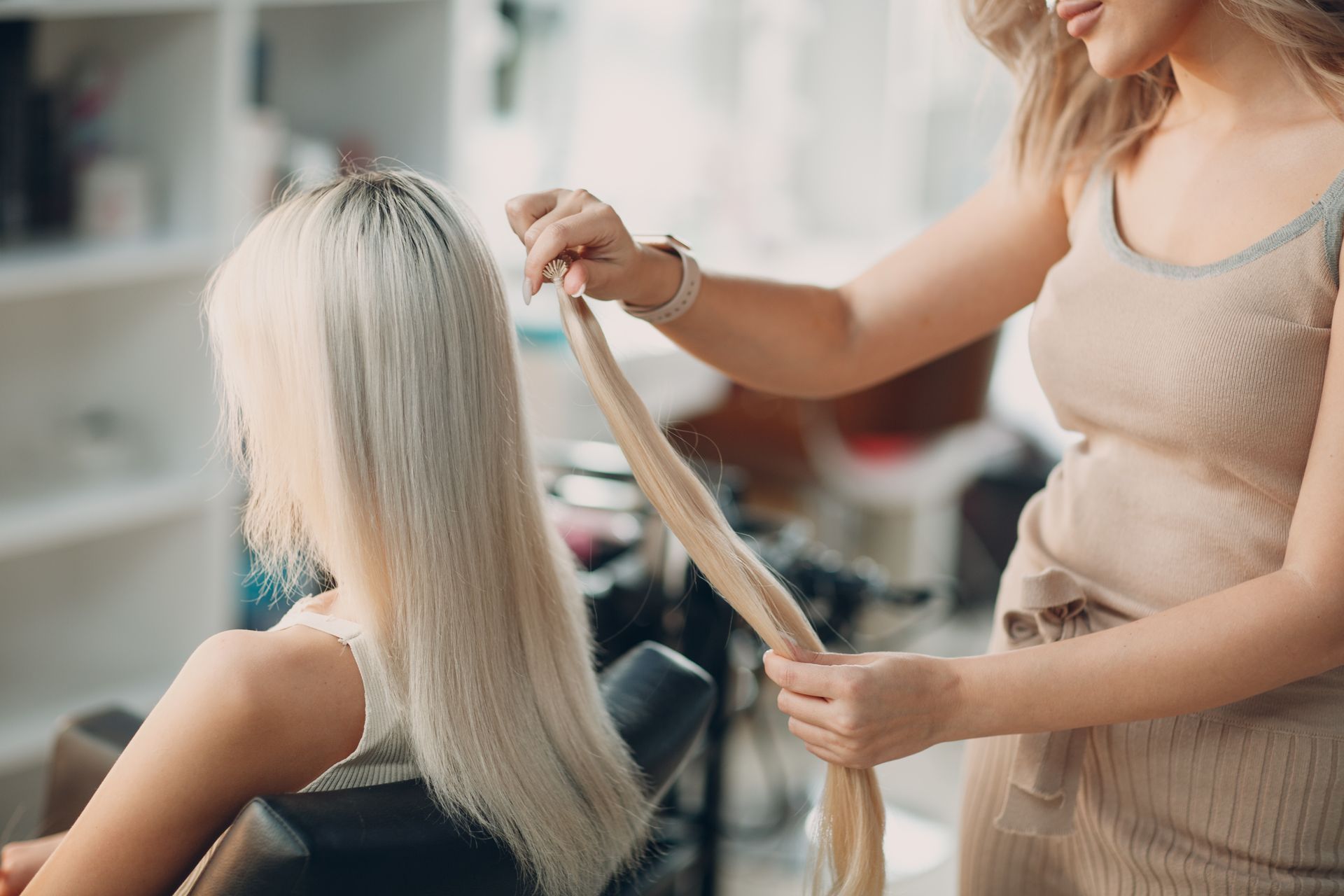 A woman is getting her hair done by a hairdresser in a salon.