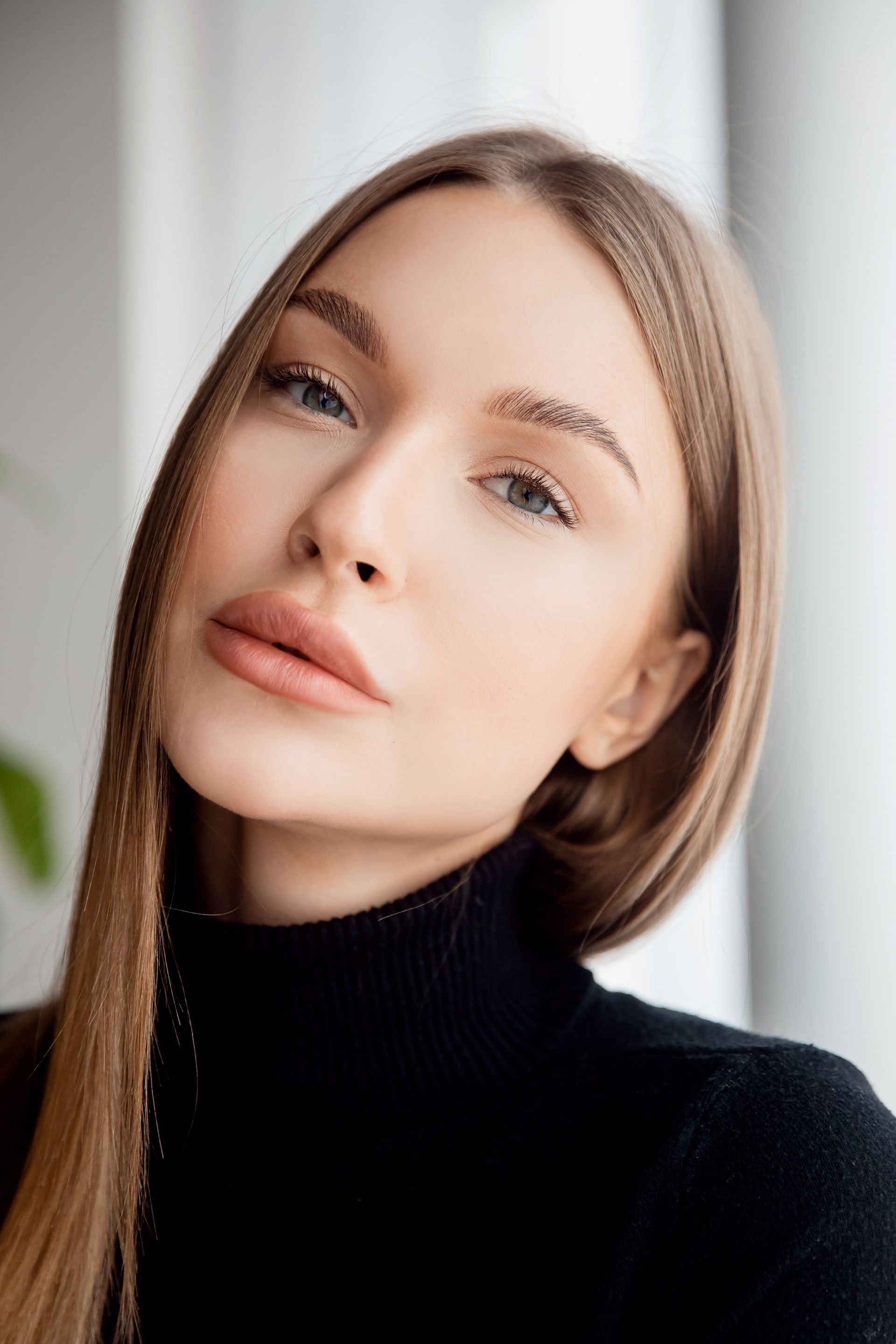 A woman with long hair is wearing a black turtleneck and looking at the camera.