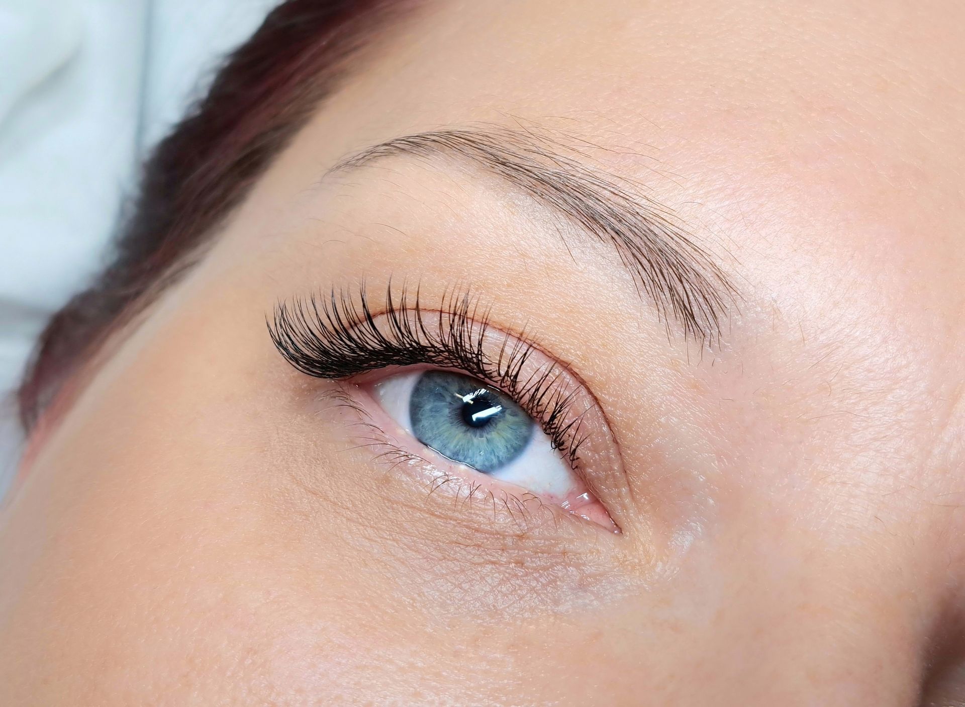 A close up of a woman 's blue eye with long eyelashes.