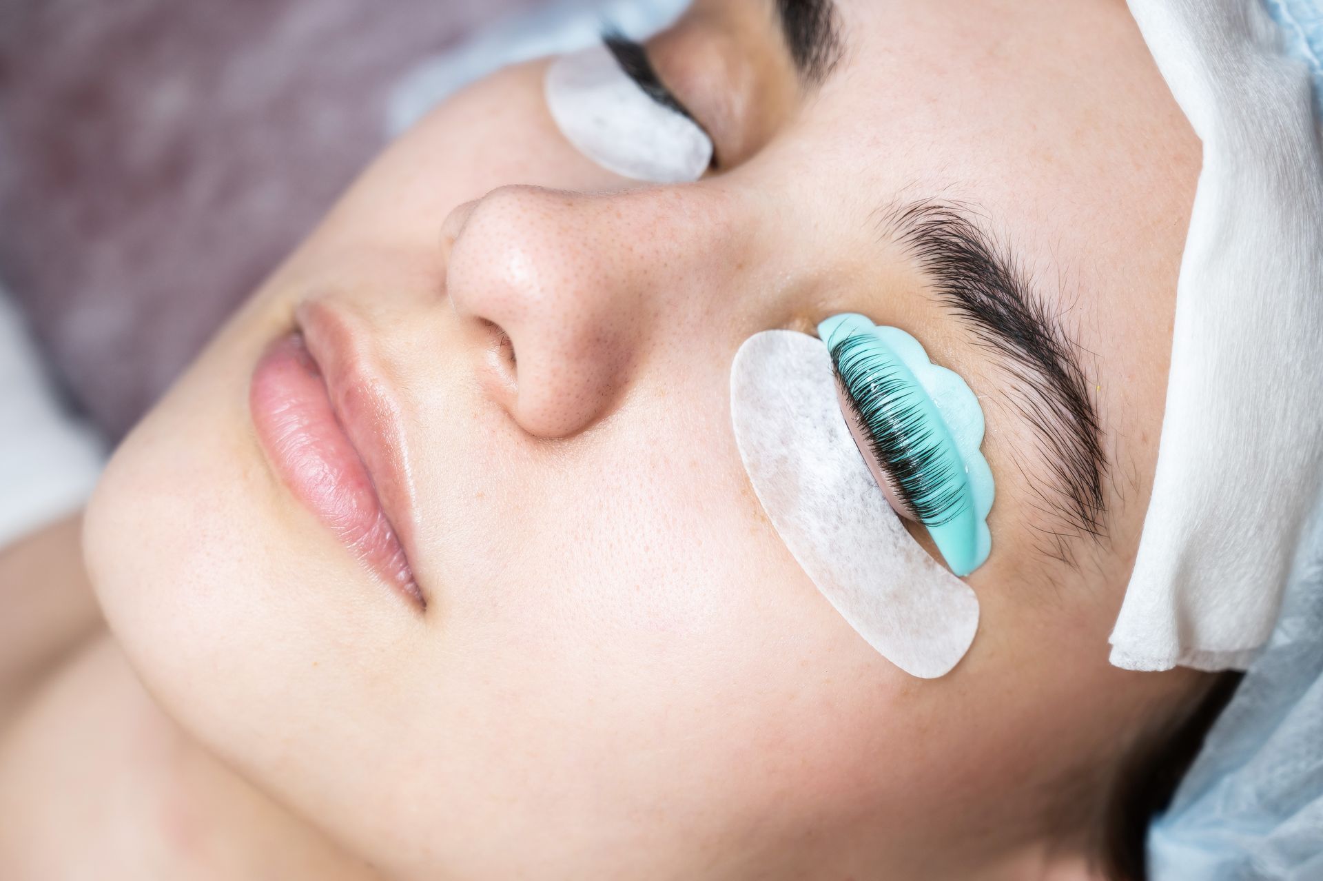 A woman is getting eyelash extensions in a beauty salon.