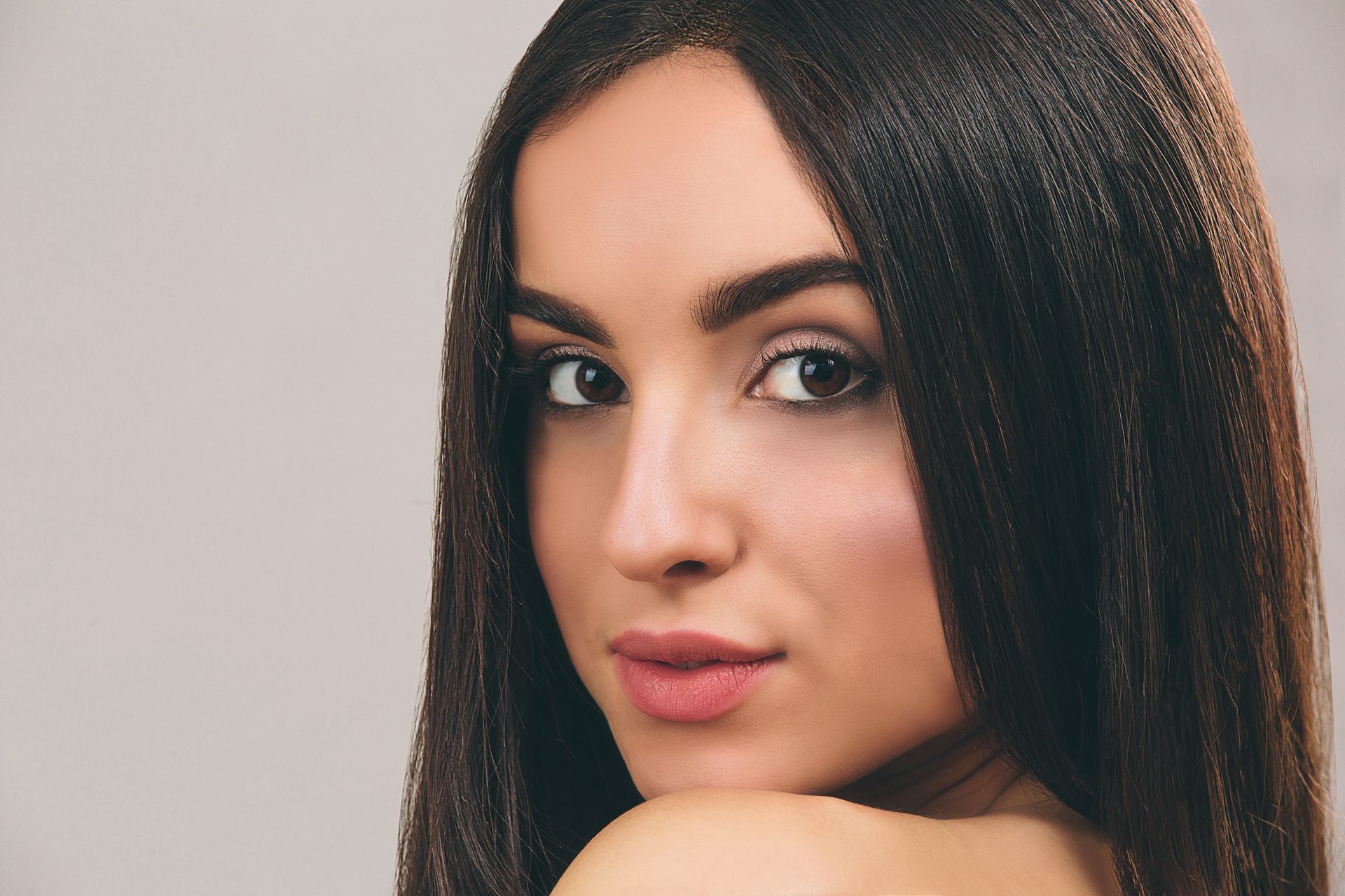 A woman with long hair is looking over her shoulder at the camera.