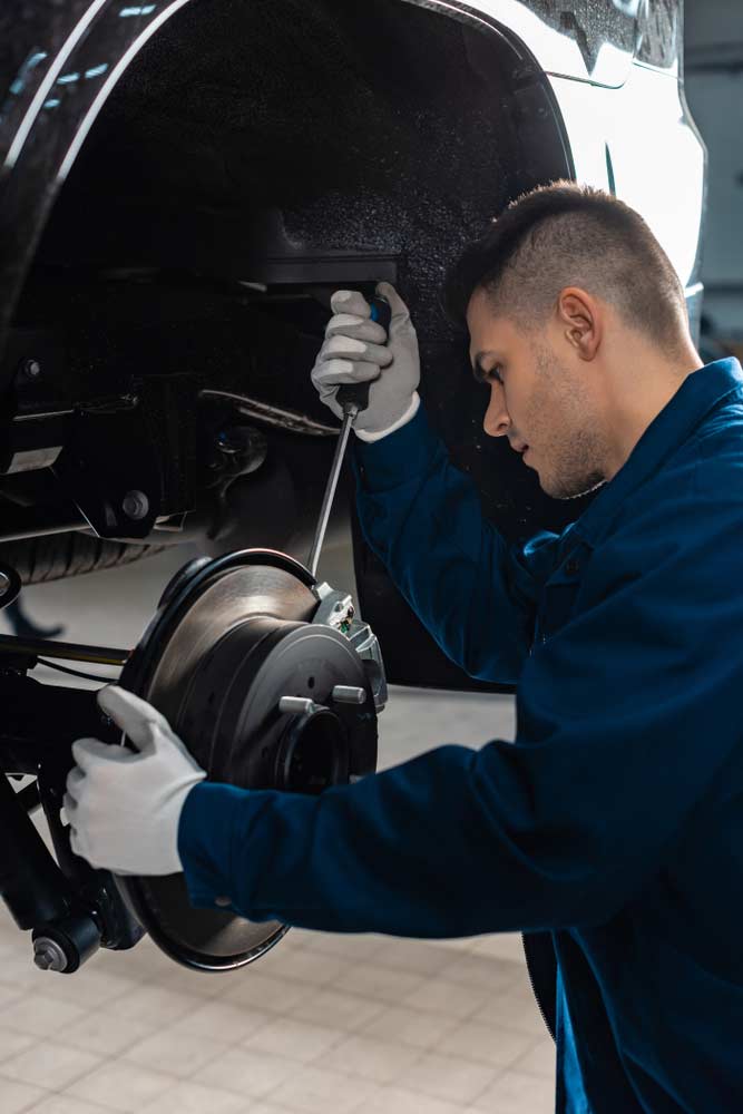 Mechanic Adjusting Brake Caliper With Screw Driver — Mechanic In Marulan, NSW