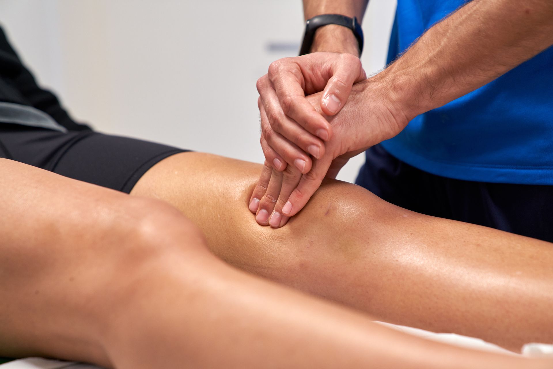 Close up of hands of physiotherapist applying pressure on a knee.