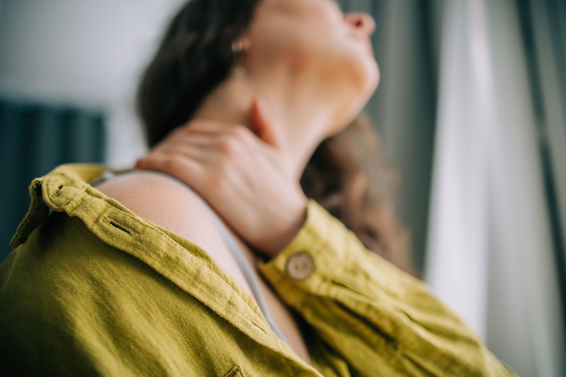 Close-up of woman with hand on sore neck.