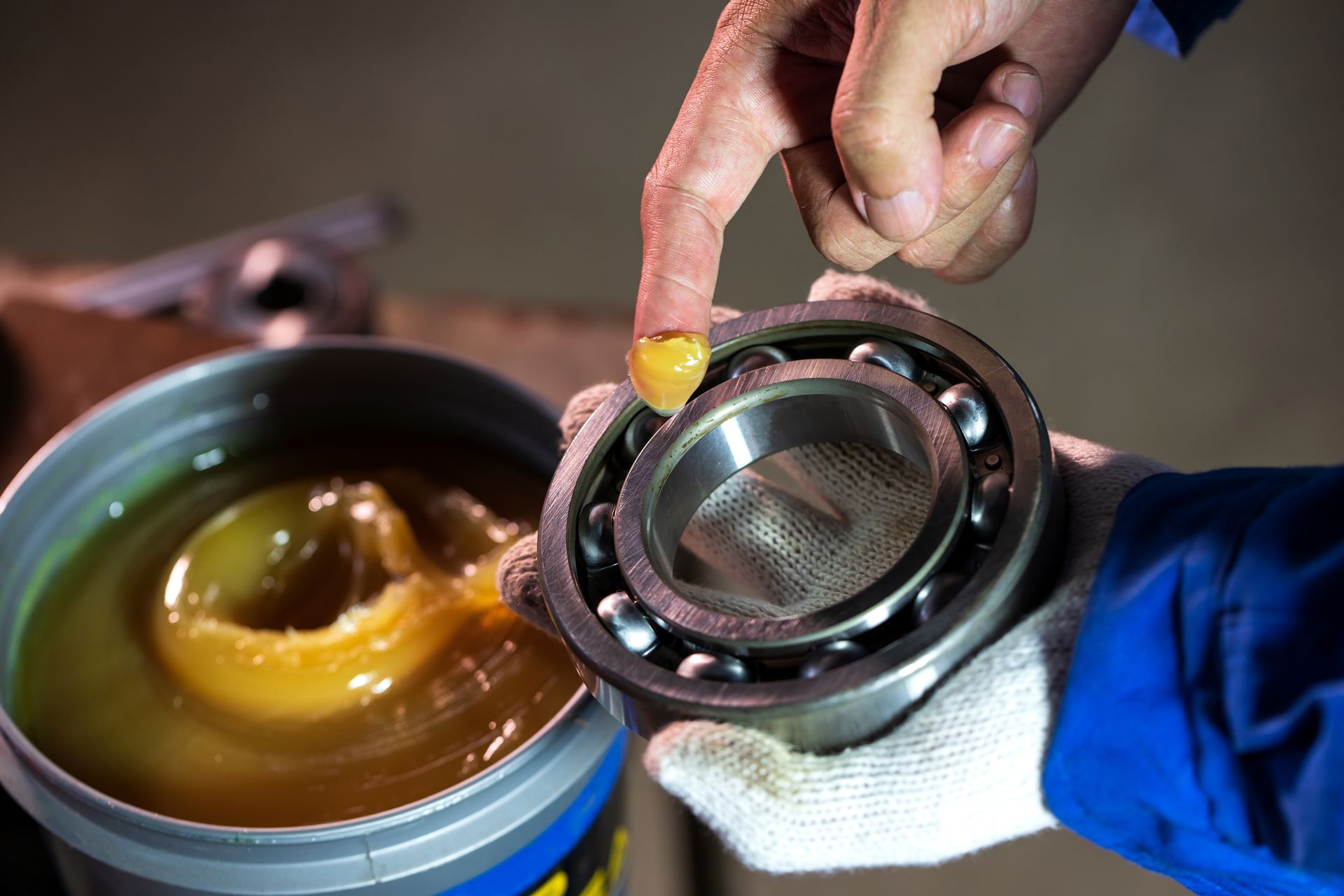 A person is applying grease to a bearing.