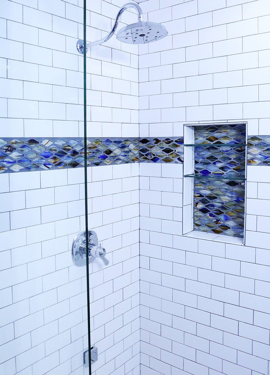 A shower with a glass door and a blue tile border.