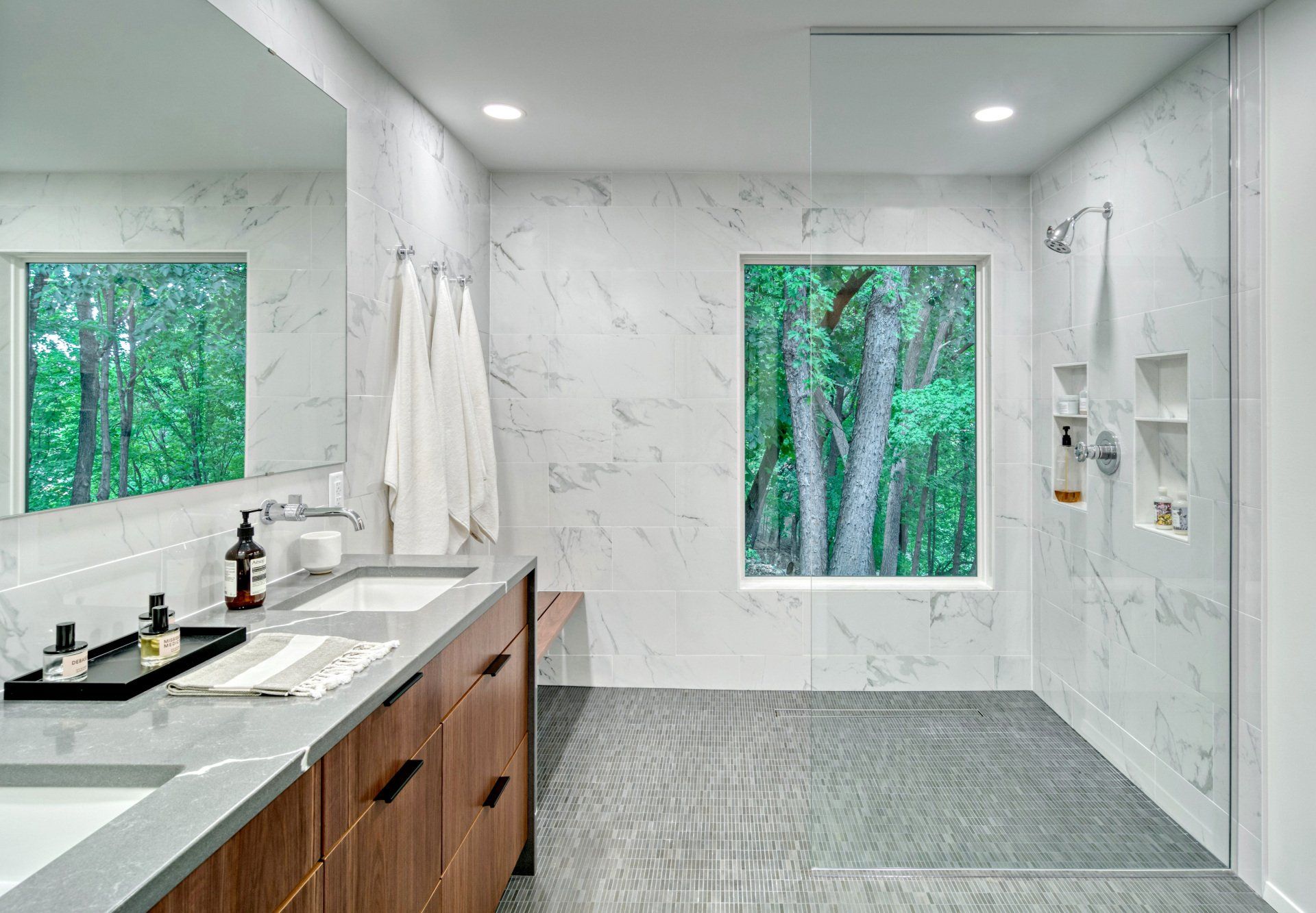 A bathroom with two sinks , a walk in shower and a large window.