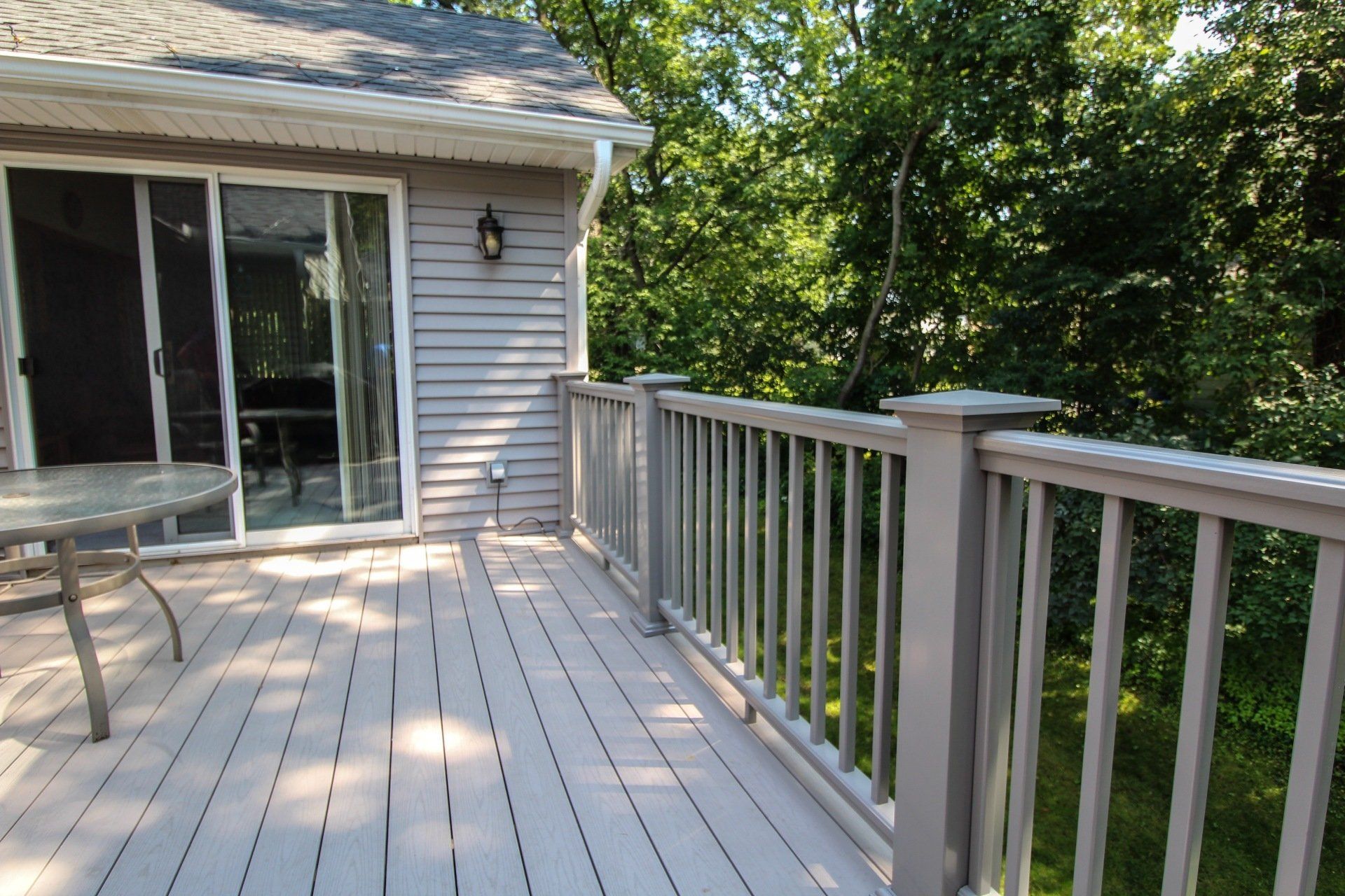 A deck with a sliding glass door and a table