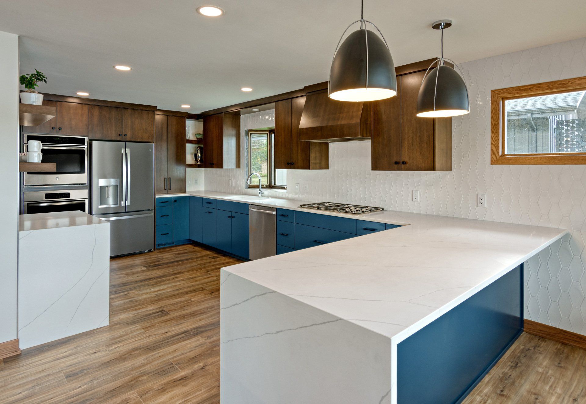 A kitchen with blue cabinets , white counter tops , and stainless steel appliances.