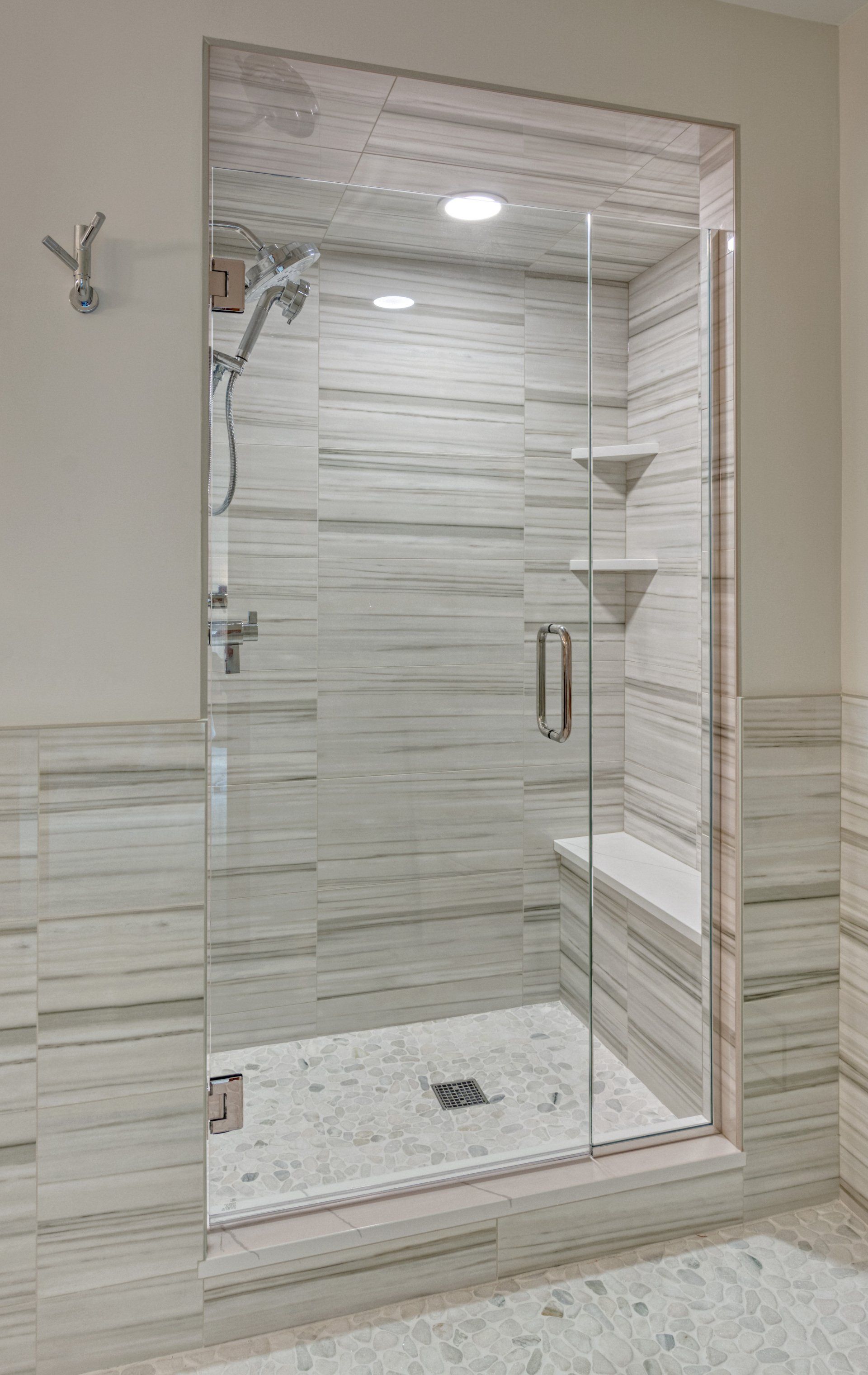 A bathroom with a walk in shower with a glass door.