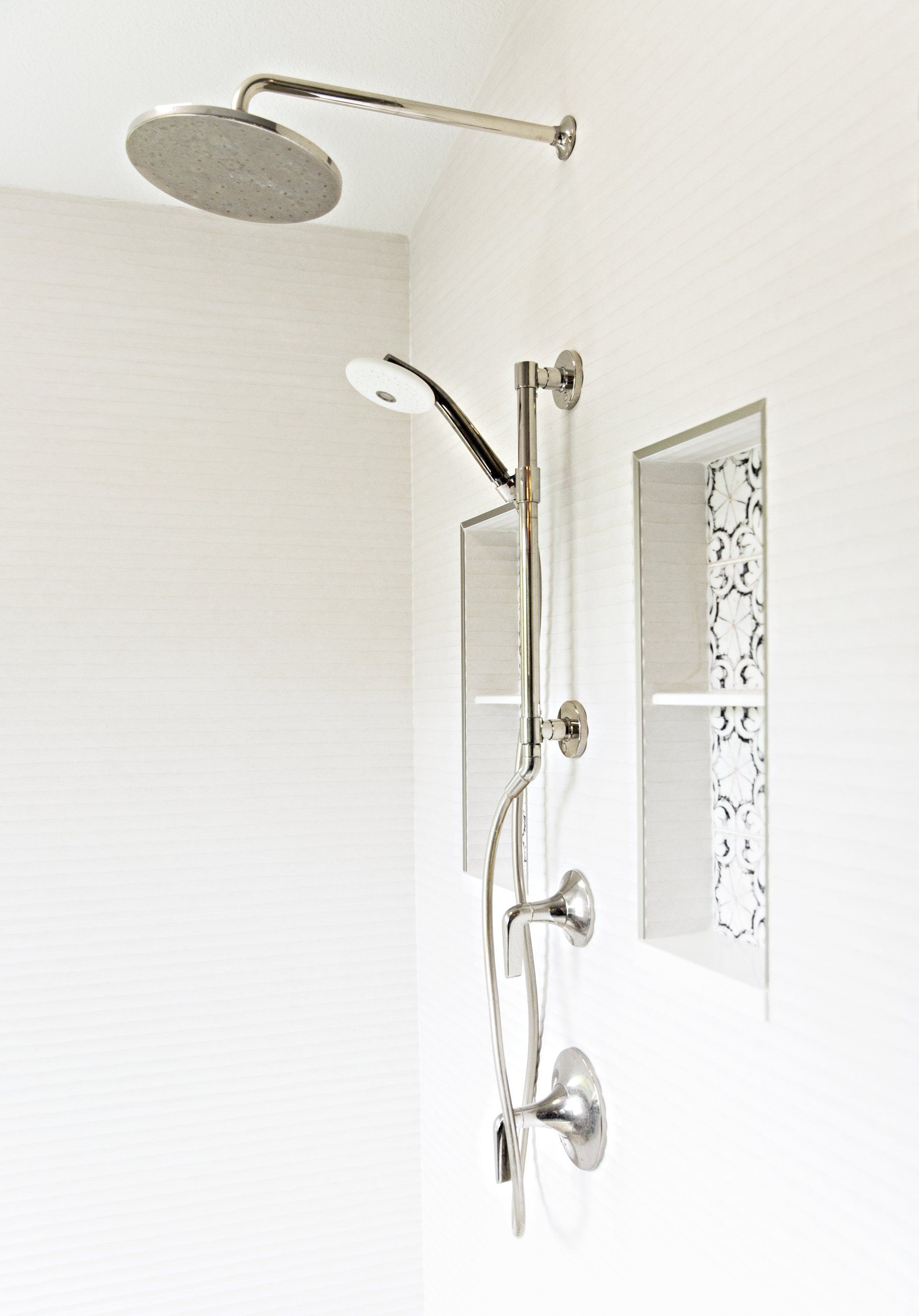 A shower head is hanging from the ceiling in a bathroom.