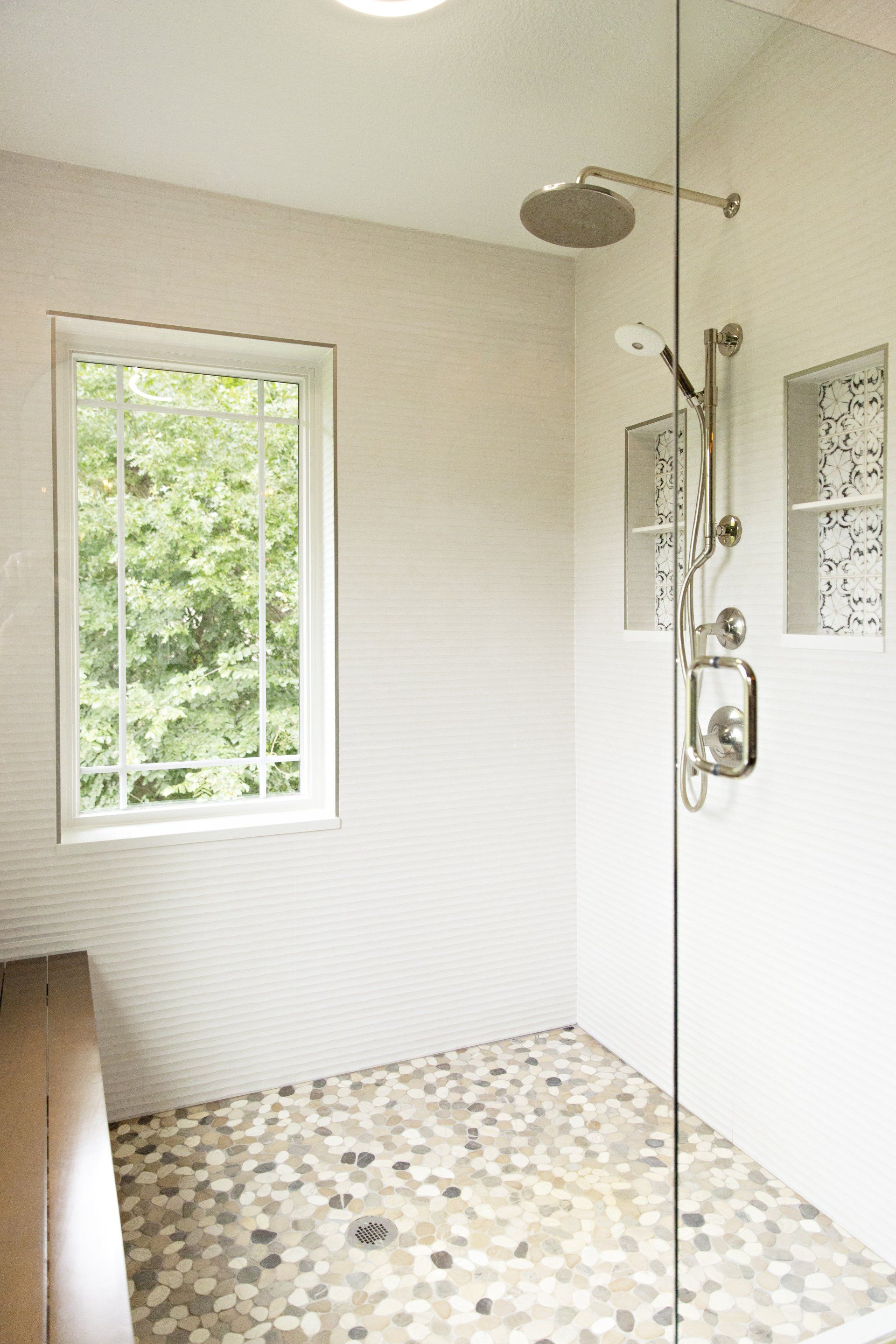 A bathroom with a walk in shower and a window.