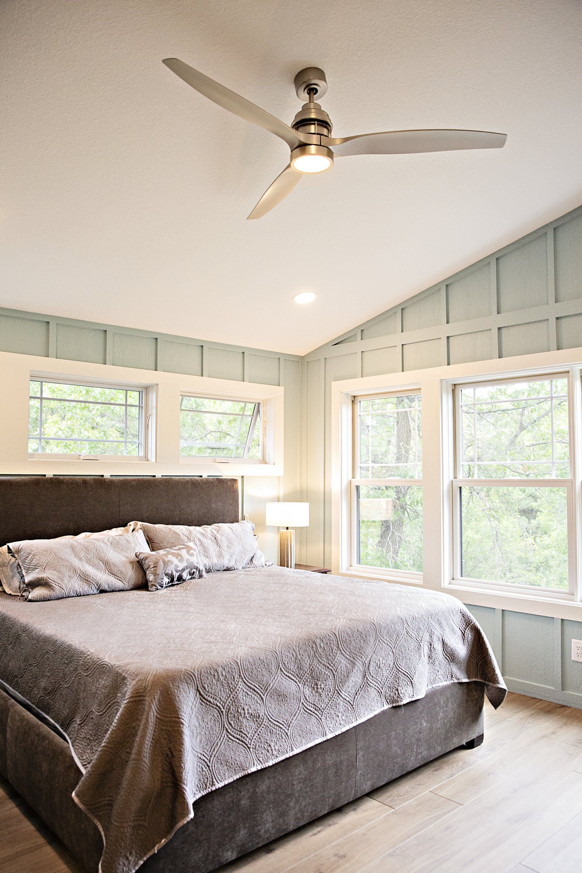 A bedroom with a large bed and a ceiling fan.