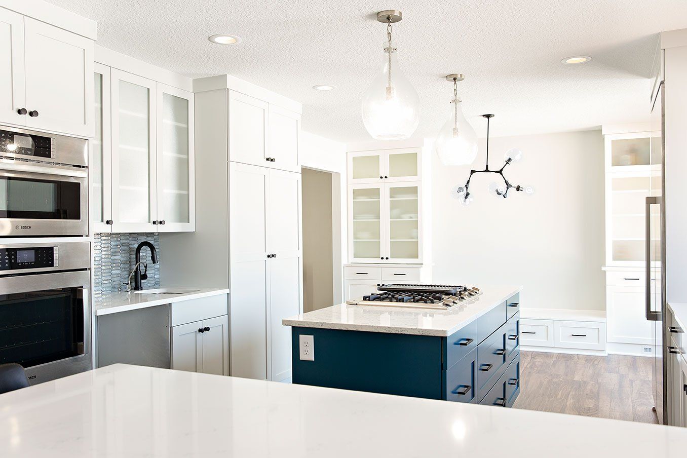 A kitchen with white cabinets , stainless steel appliances , and a blue island.
