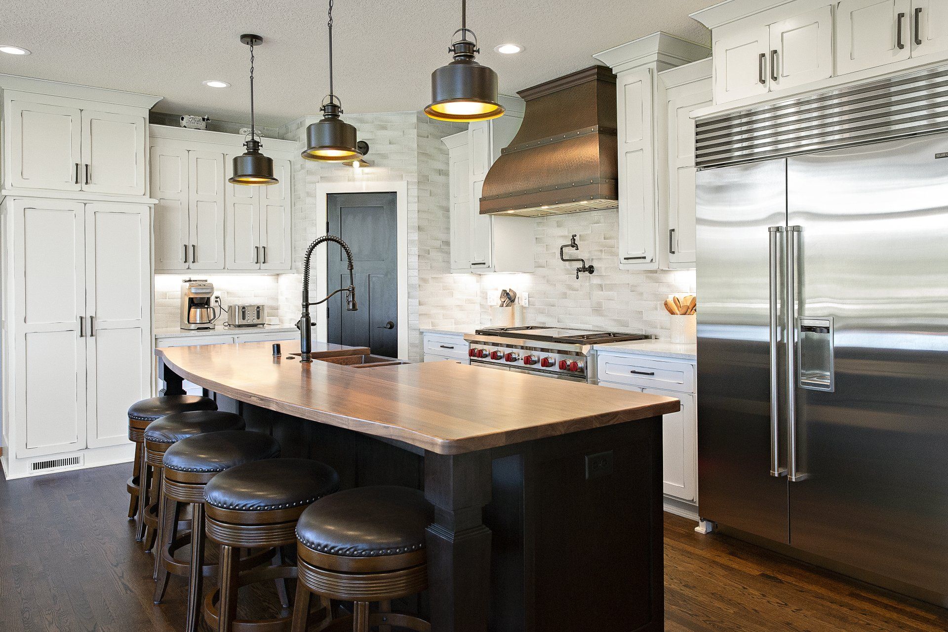 A kitchen with white cabinets , stainless steel appliances and a large island.