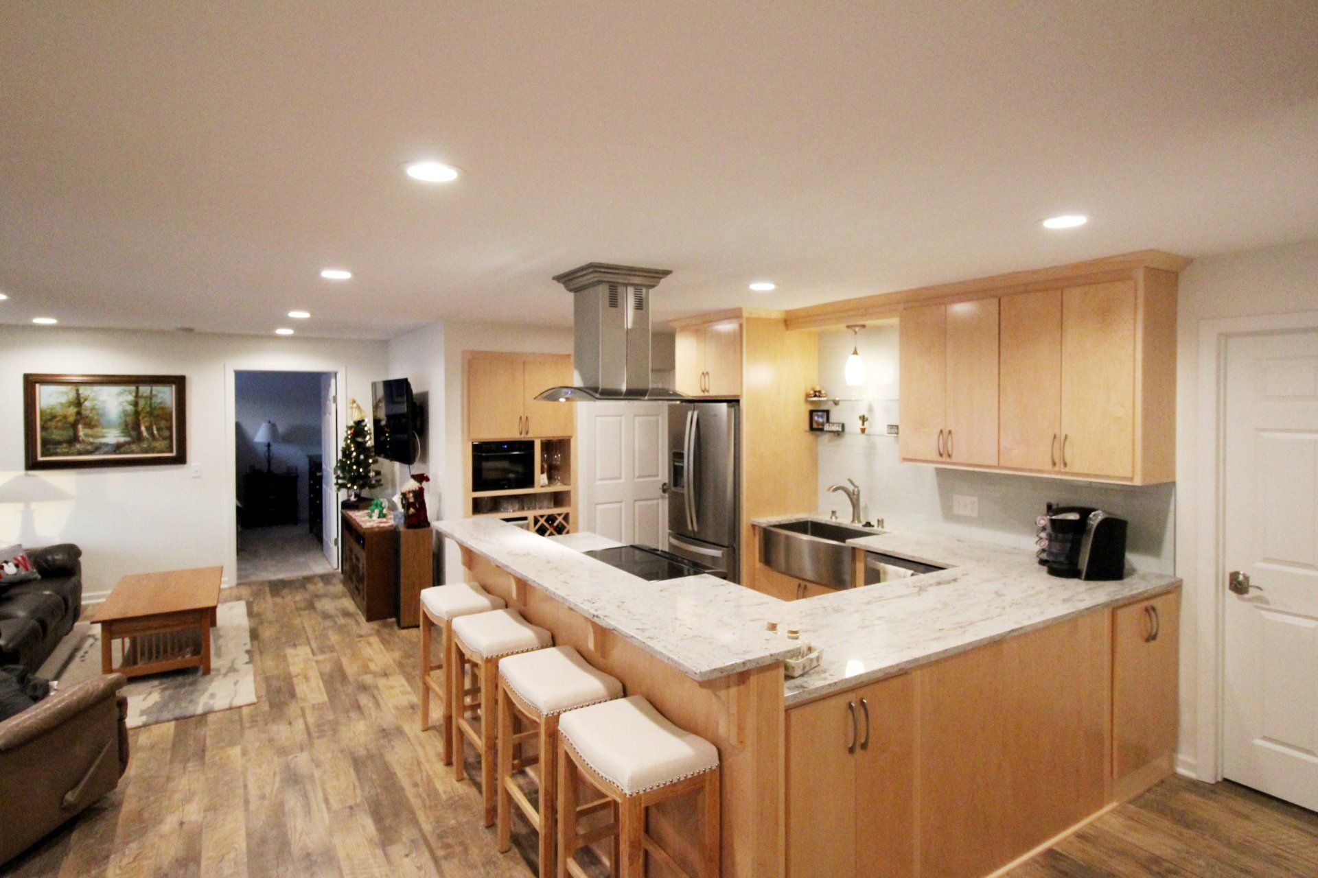 A kitchen with a large island and stools in a living room.
