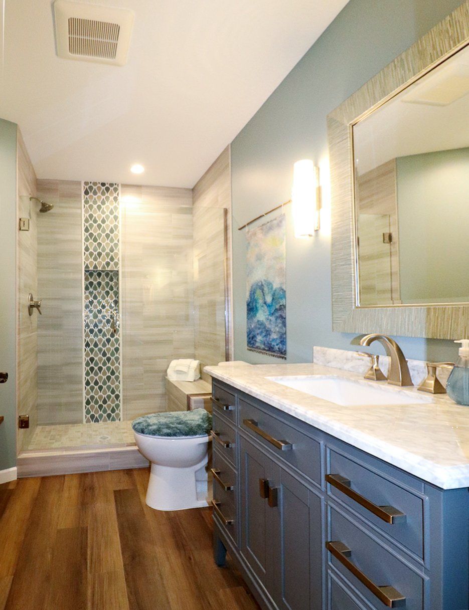A bathroom with a toilet , sink , mirror and shower.