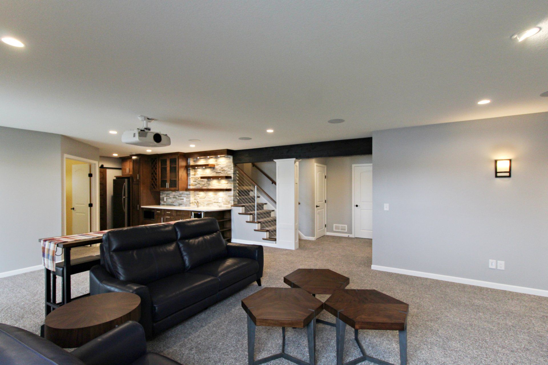 A living room with a couch , chairs , tables and a projector screen.