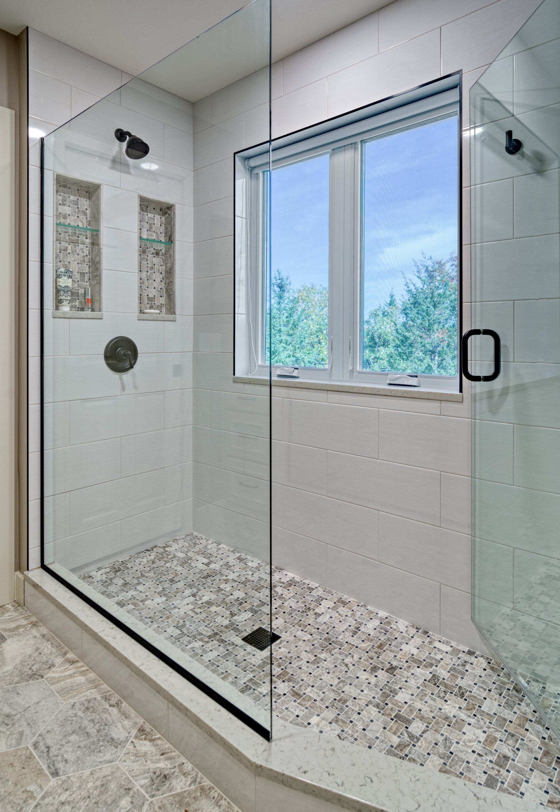 A bathroom with a walk in shower and a window.