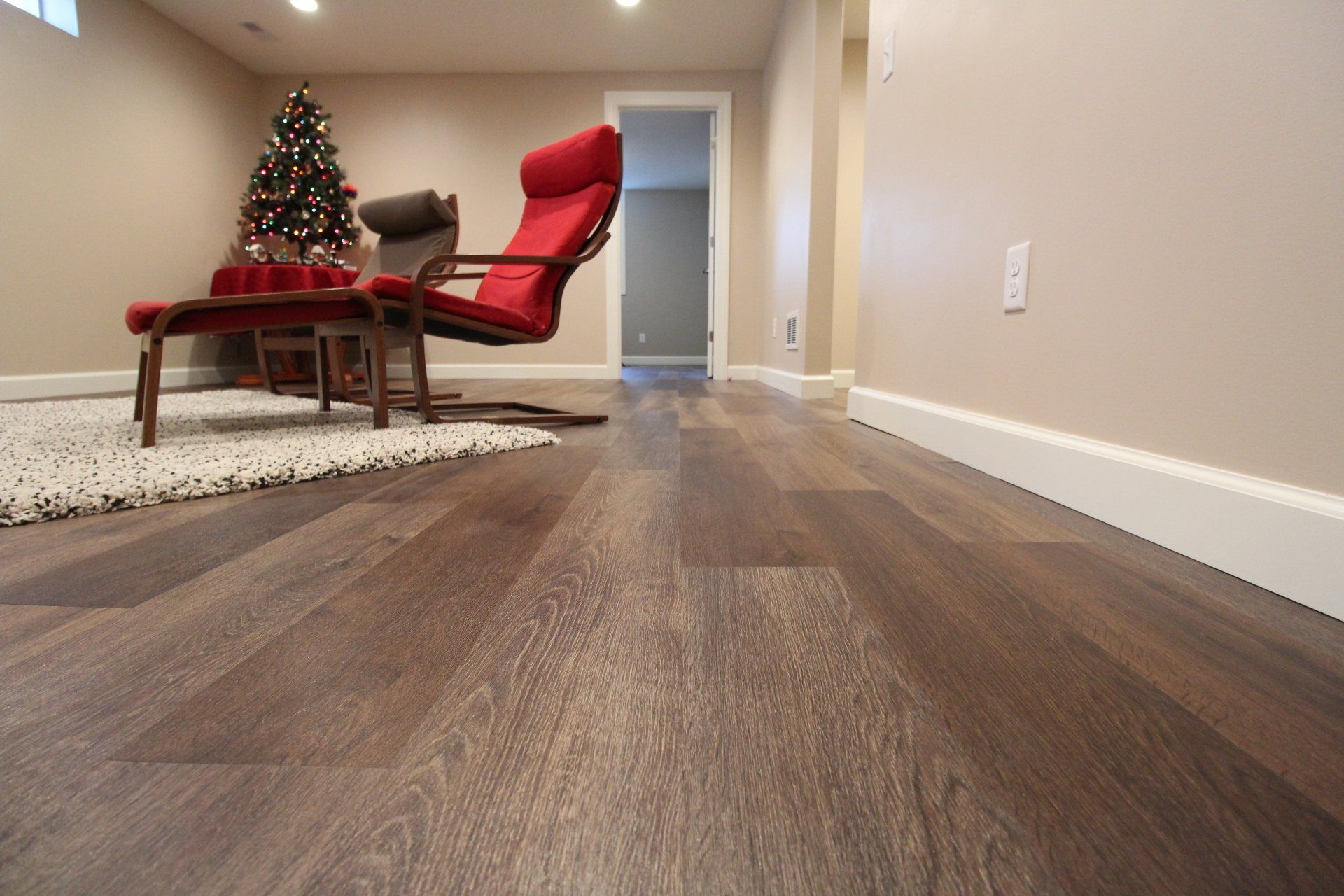 A living room with hardwood floors and a christmas tree in the background.