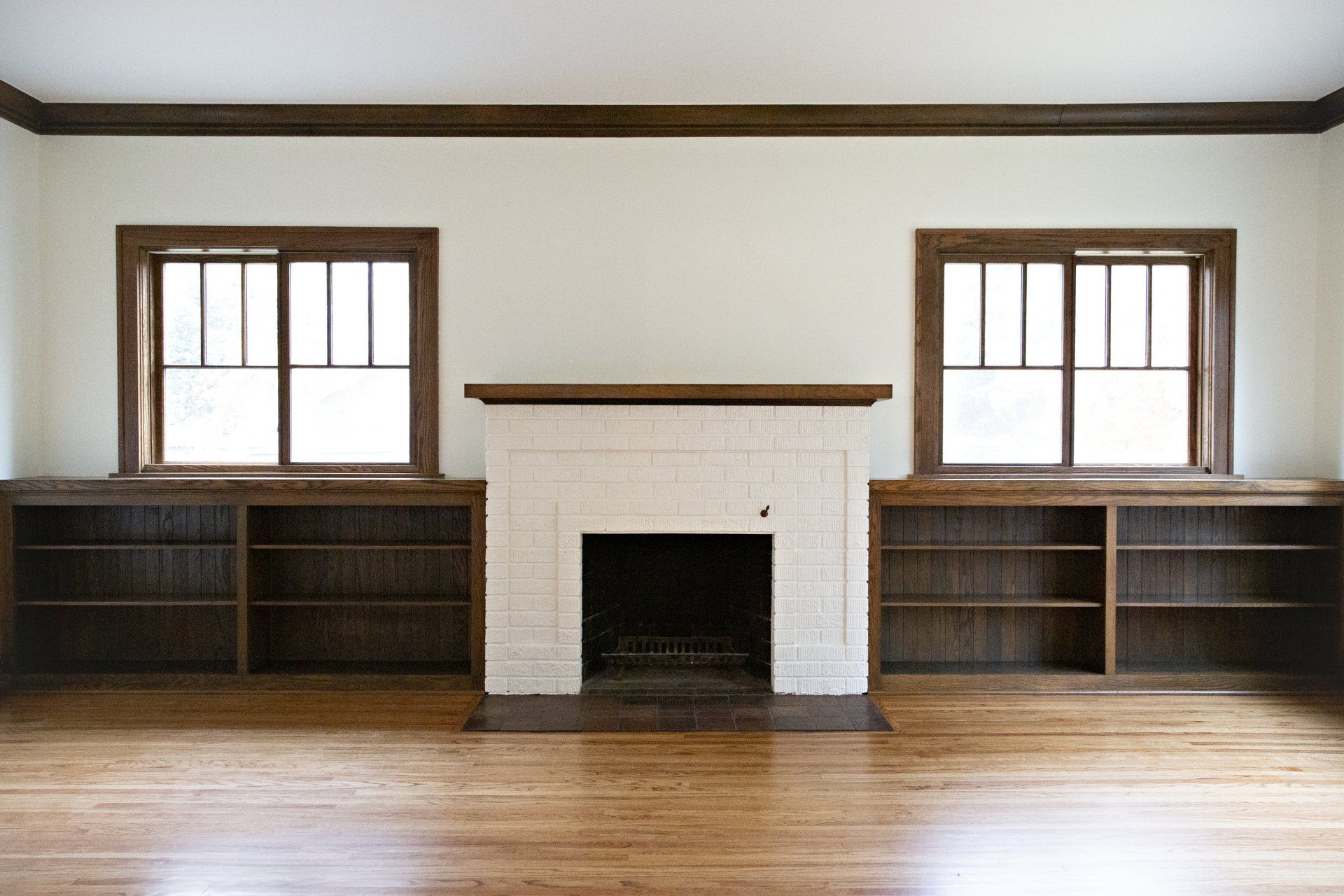 An empty living room with a fireplace and shelves