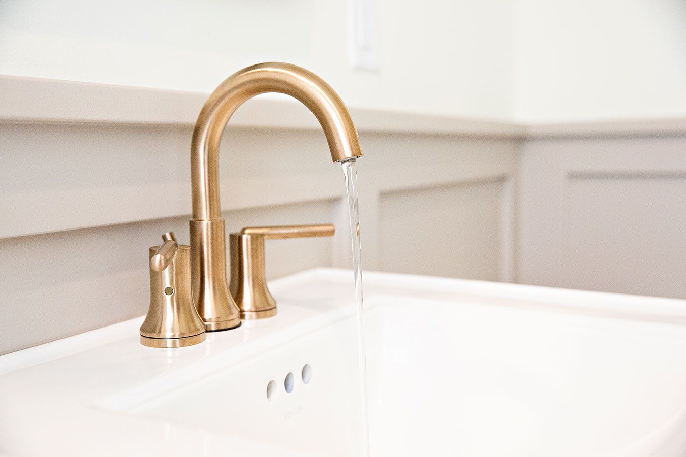 A bathroom sink with a gold faucet and water running out of it.