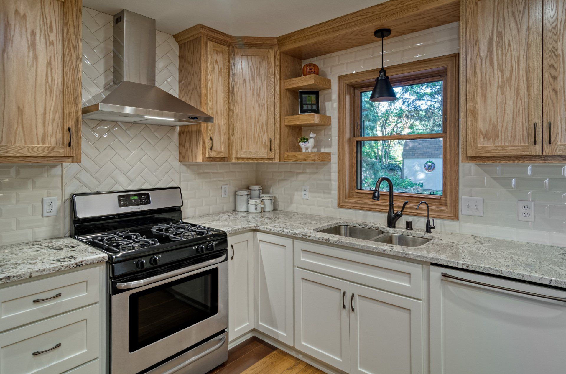 A kitchen with stainless steel appliances , white cabinets , granite counter tops and a window.