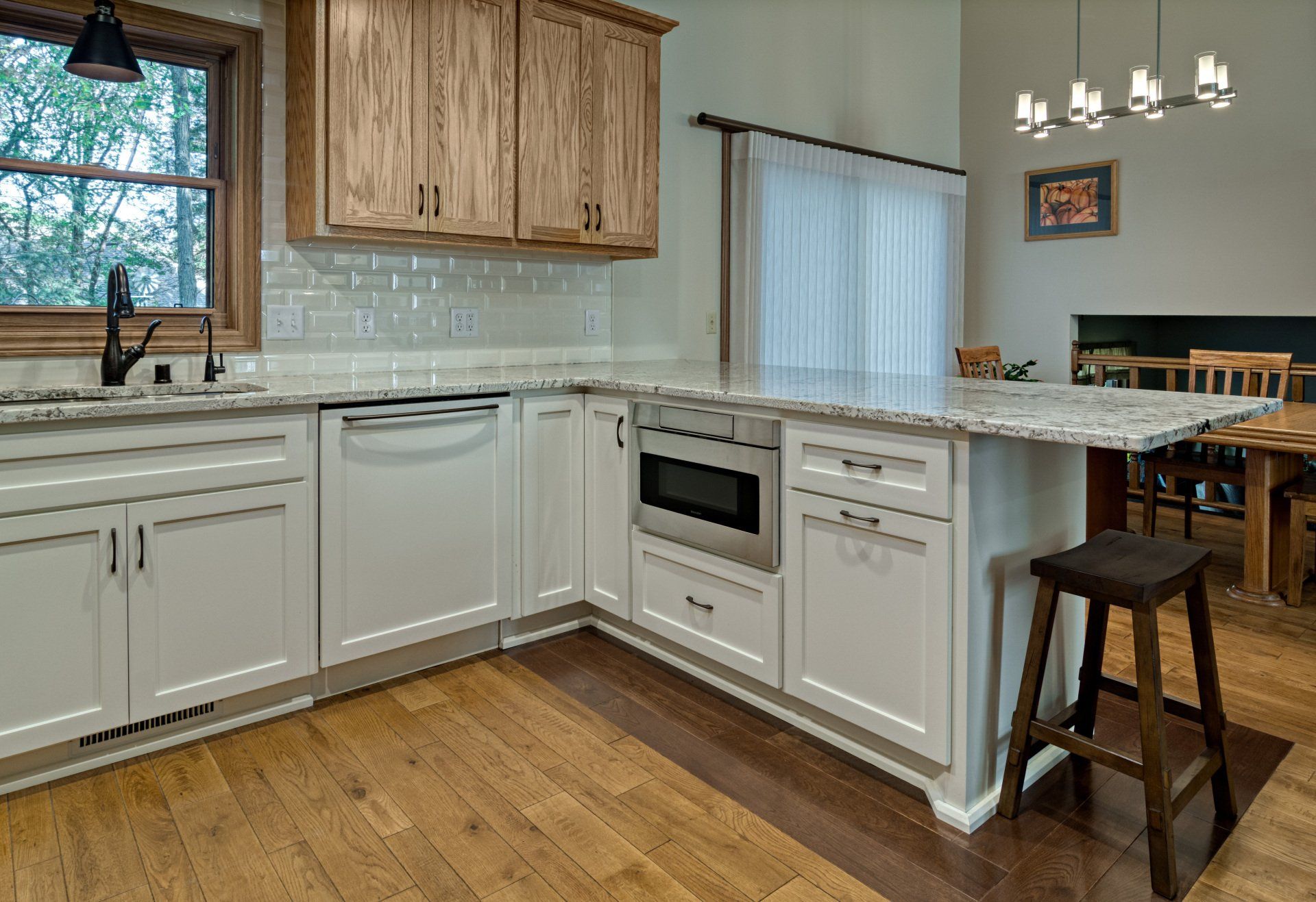 A kitchen with white cabinets , granite counter tops , stainless steel appliances , and hardwood floors.