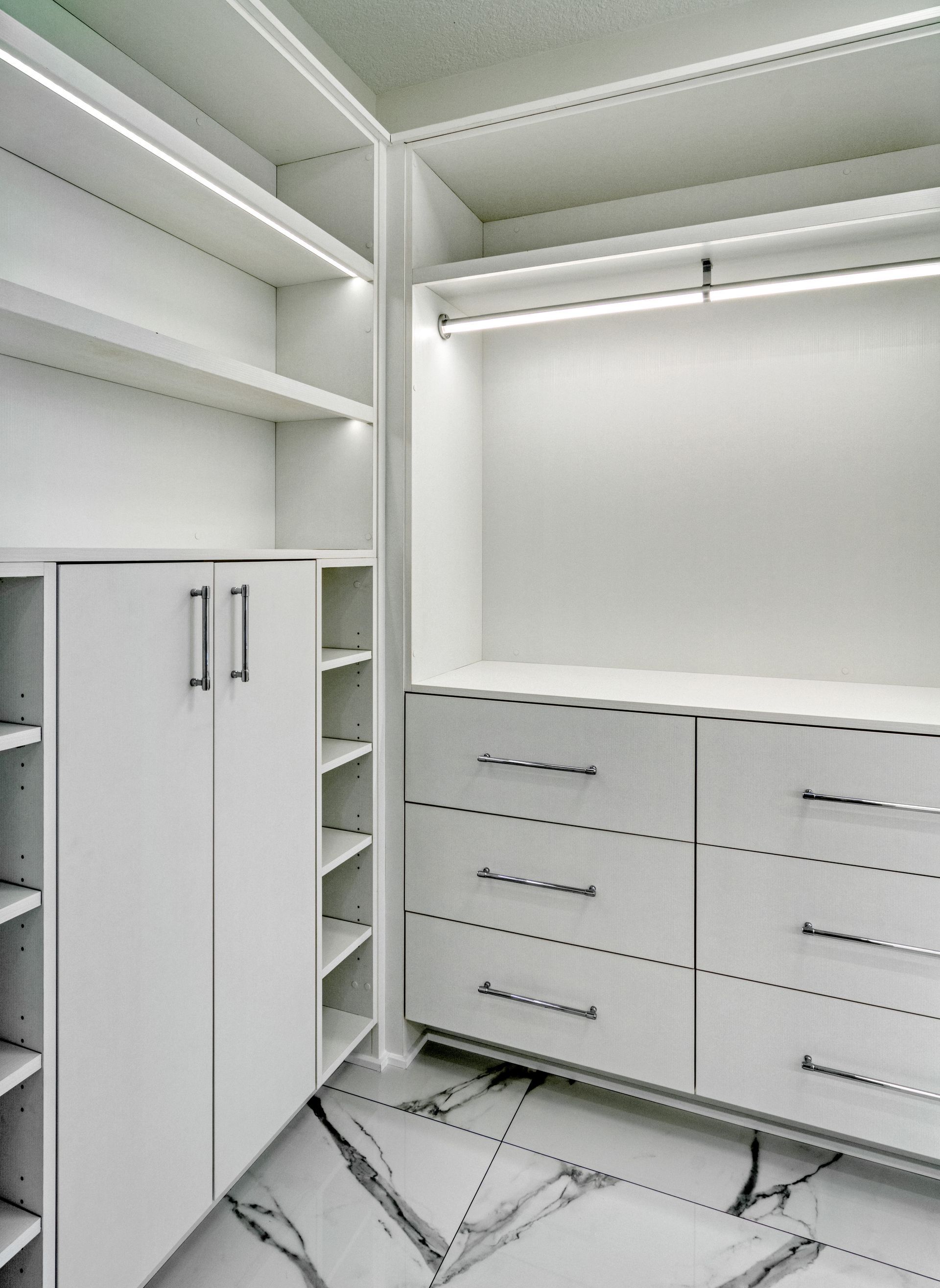 A walk in closet with white cabinets and drawers