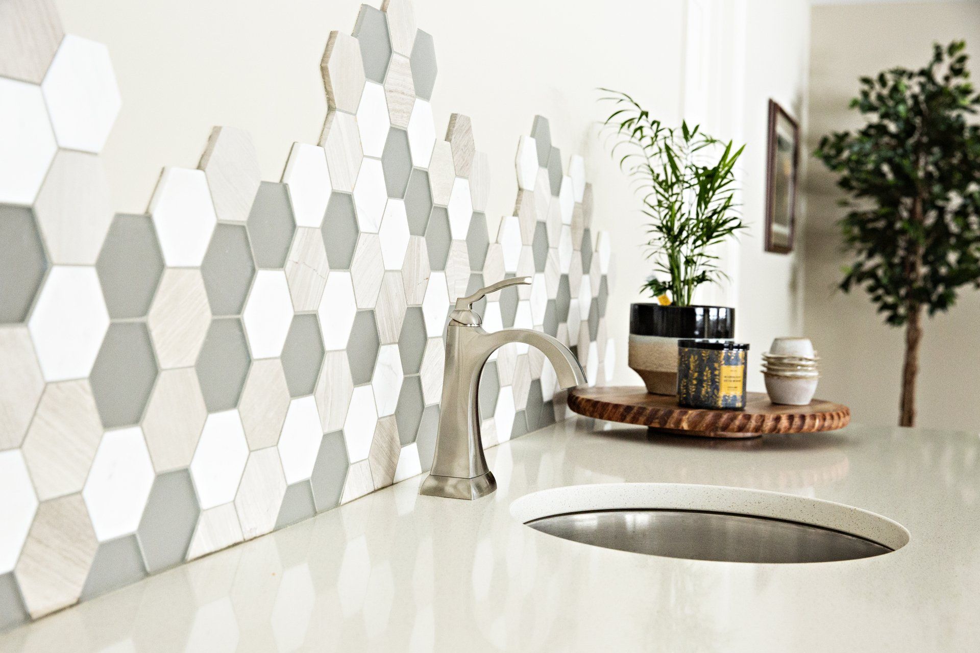 A bathroom with a sink , faucet , and hexagon tiles on the wall.