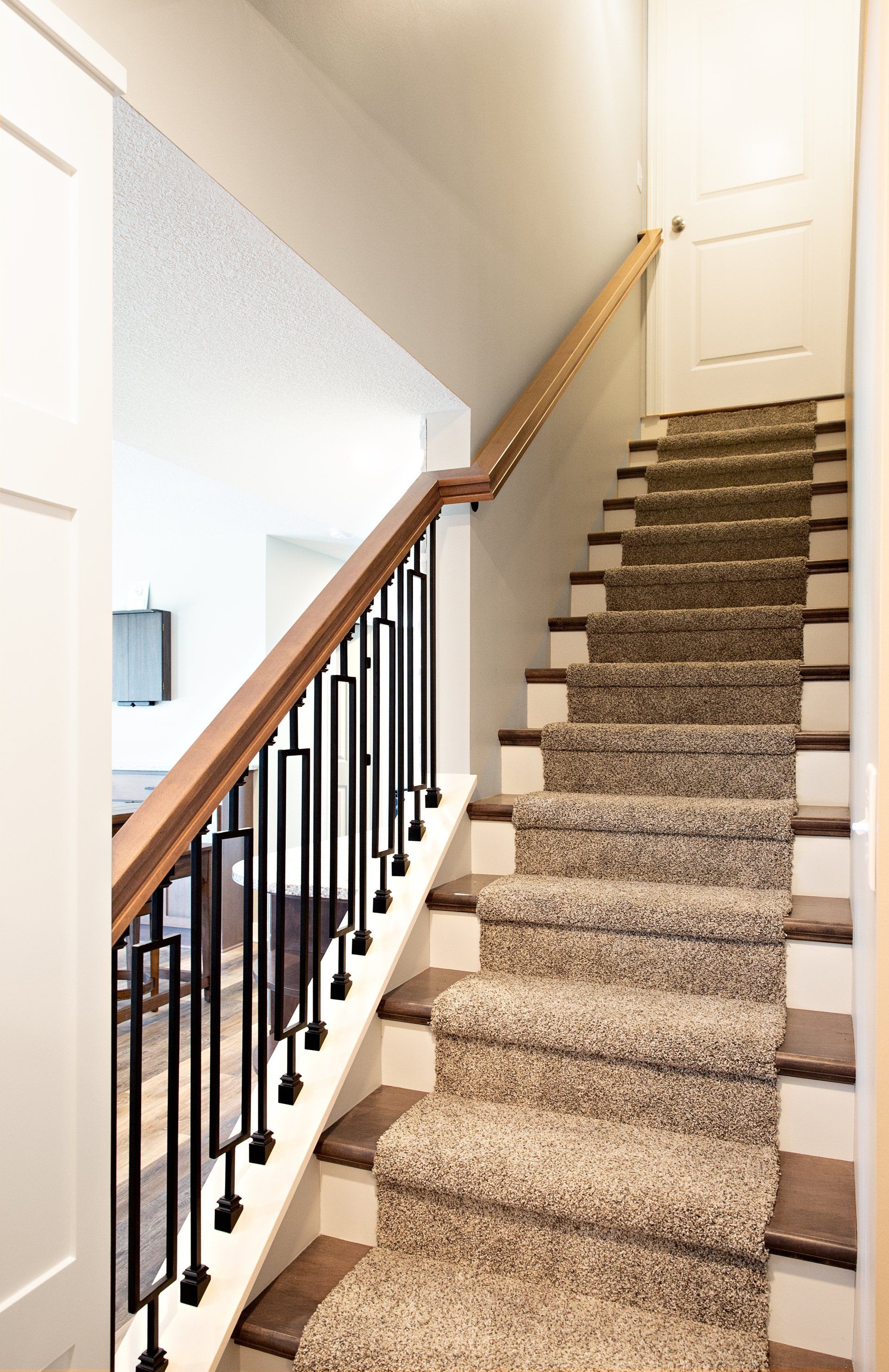 A staircase with a carpeted staircase and a wooden railing in a house.
