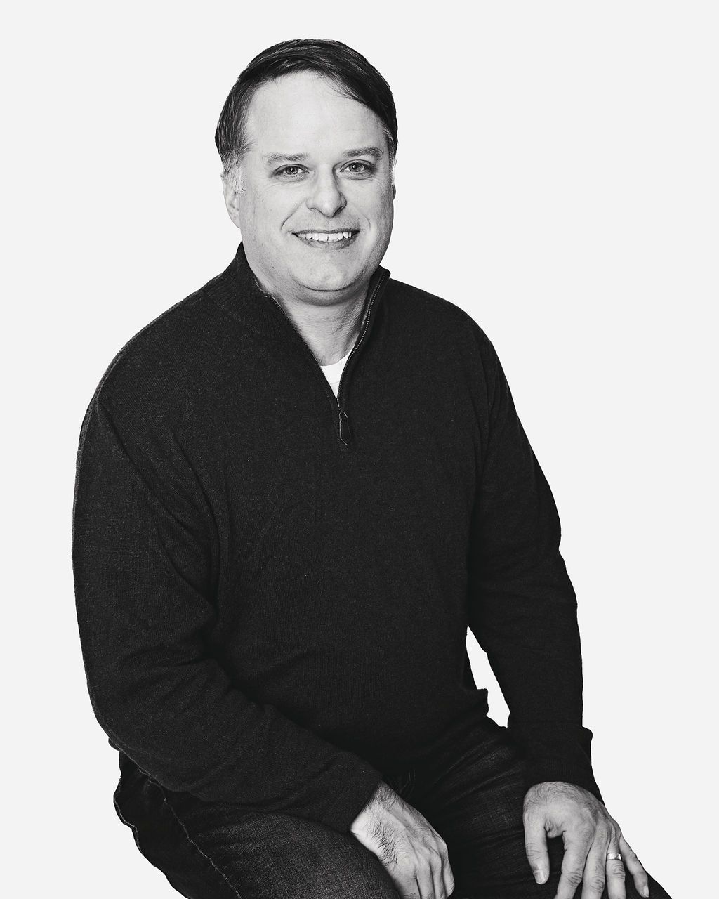 A man in a white shirt and tie is smiling in a black and white photo