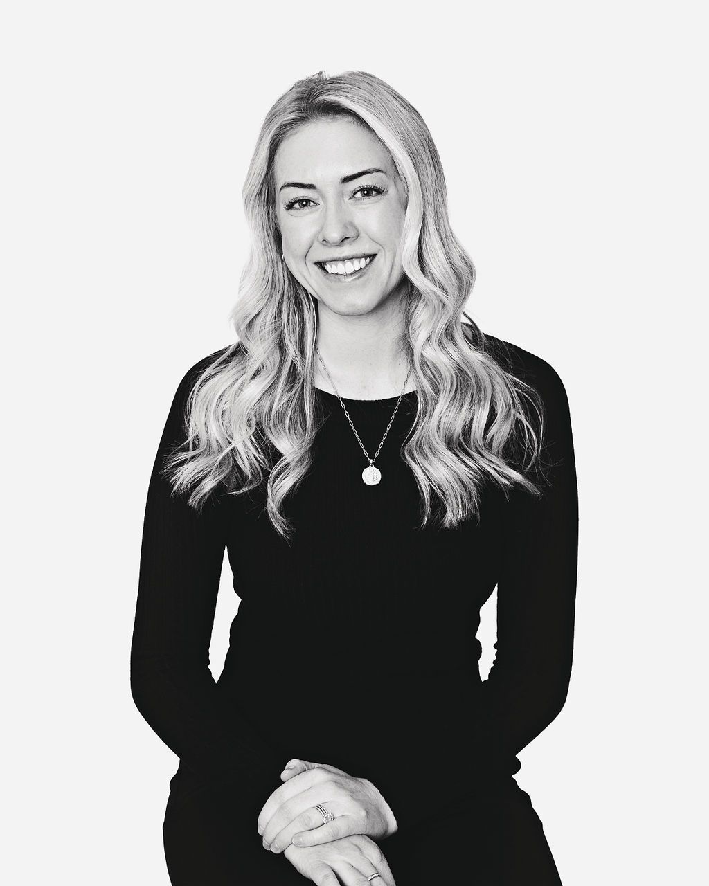 A black and white photo of a woman wearing a black dress and a necklace.