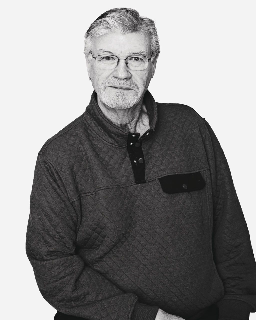 A man with glasses and a beard is wearing a grey sweater