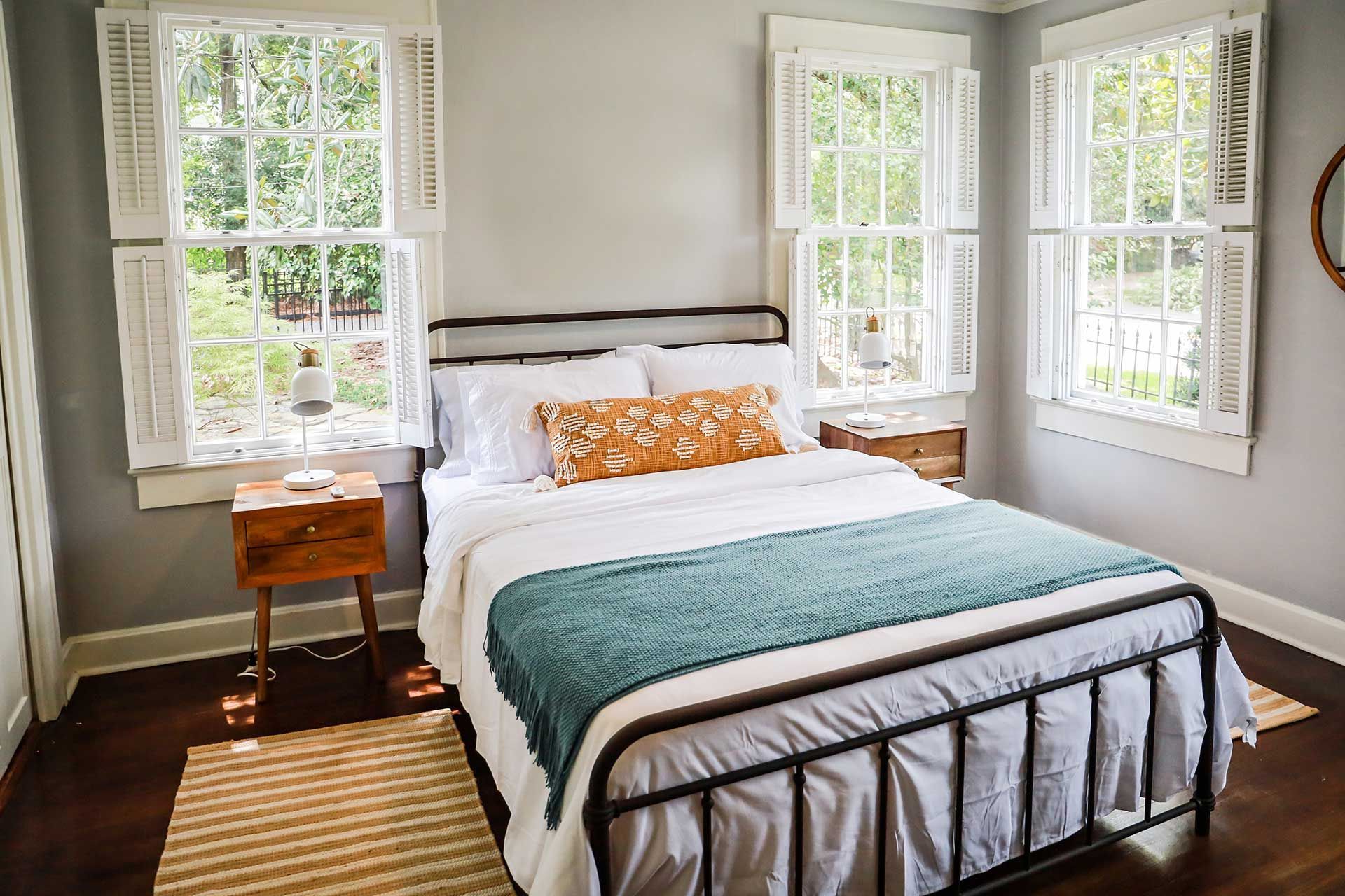 A bedroom with a bed , two nightstands , and two windows.